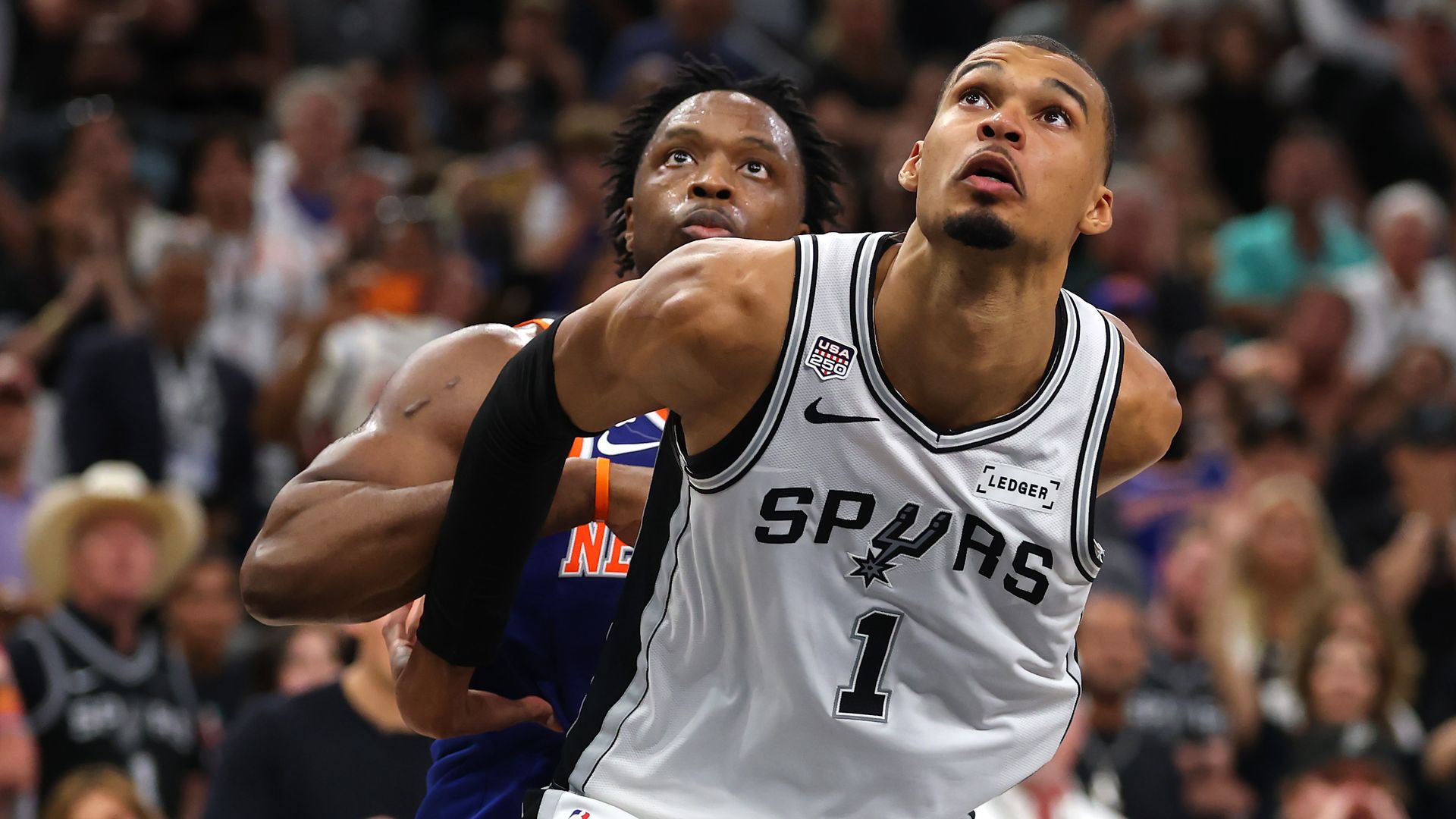 Victor Wembanyama boxes out OG Anunoby of the New York Knicks during Game Five of the NBA Finals in June. Wemby is seen in front of Anunoby and both are looking upward.