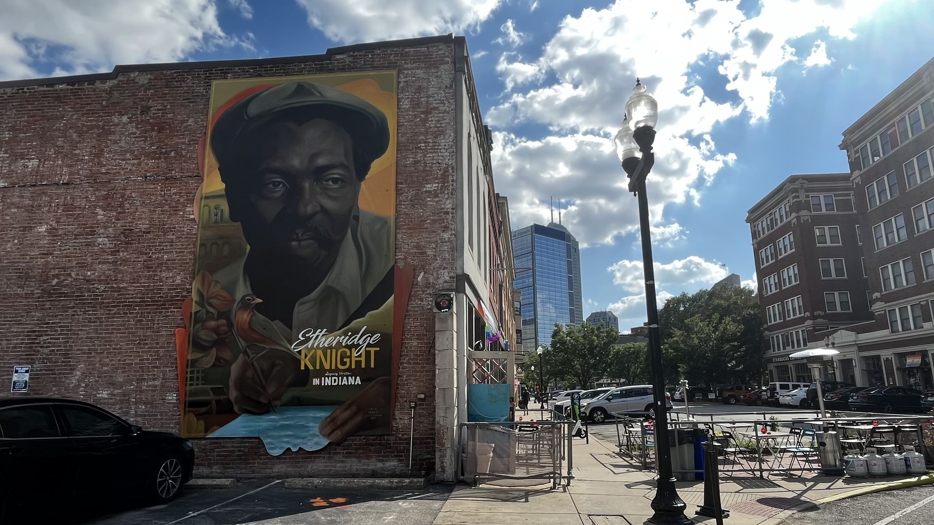 A mural on the side of a brick building on an avenue.