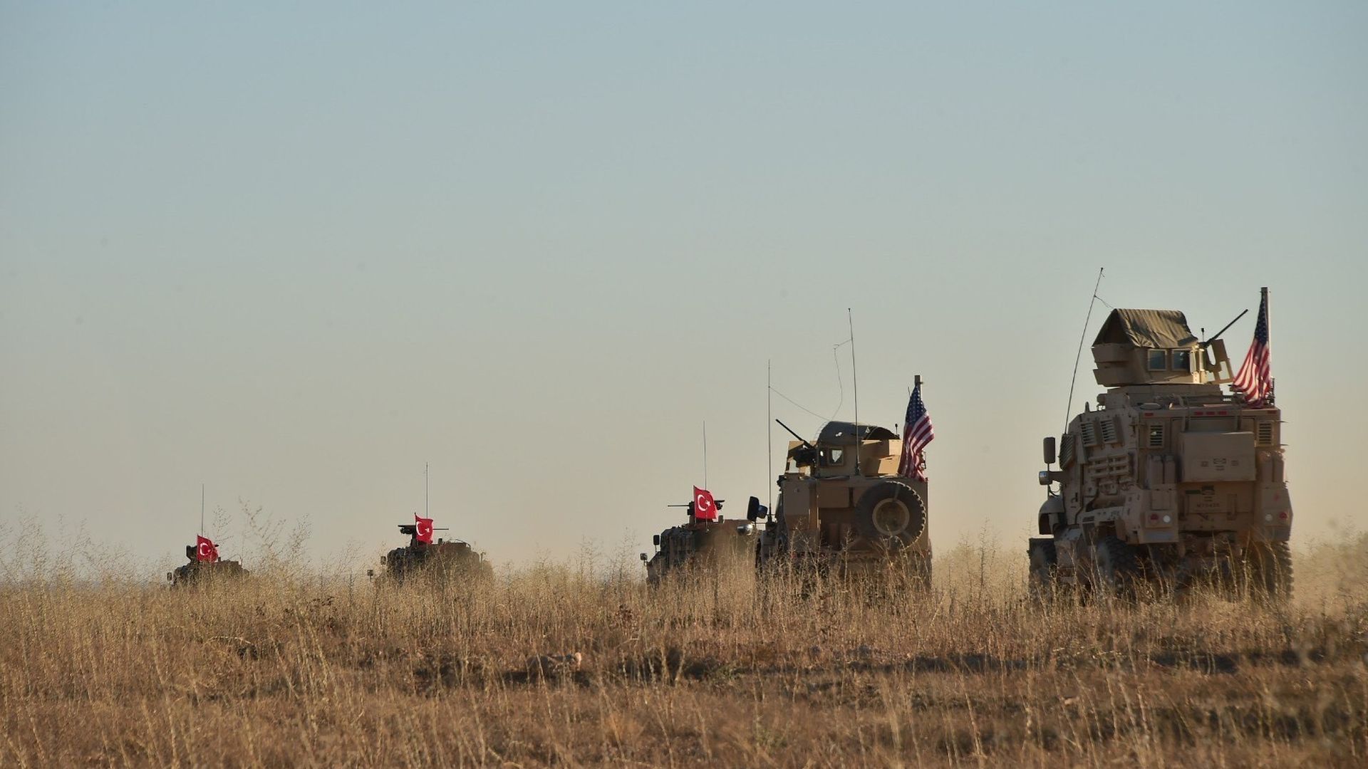 Armored vehicles with American flags flying from them.