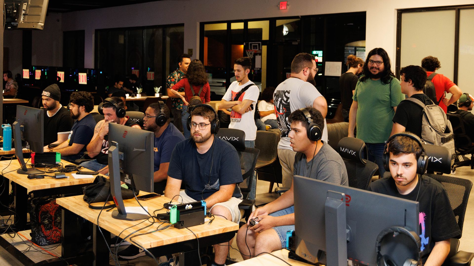 Gamers sit a desks and face computers 