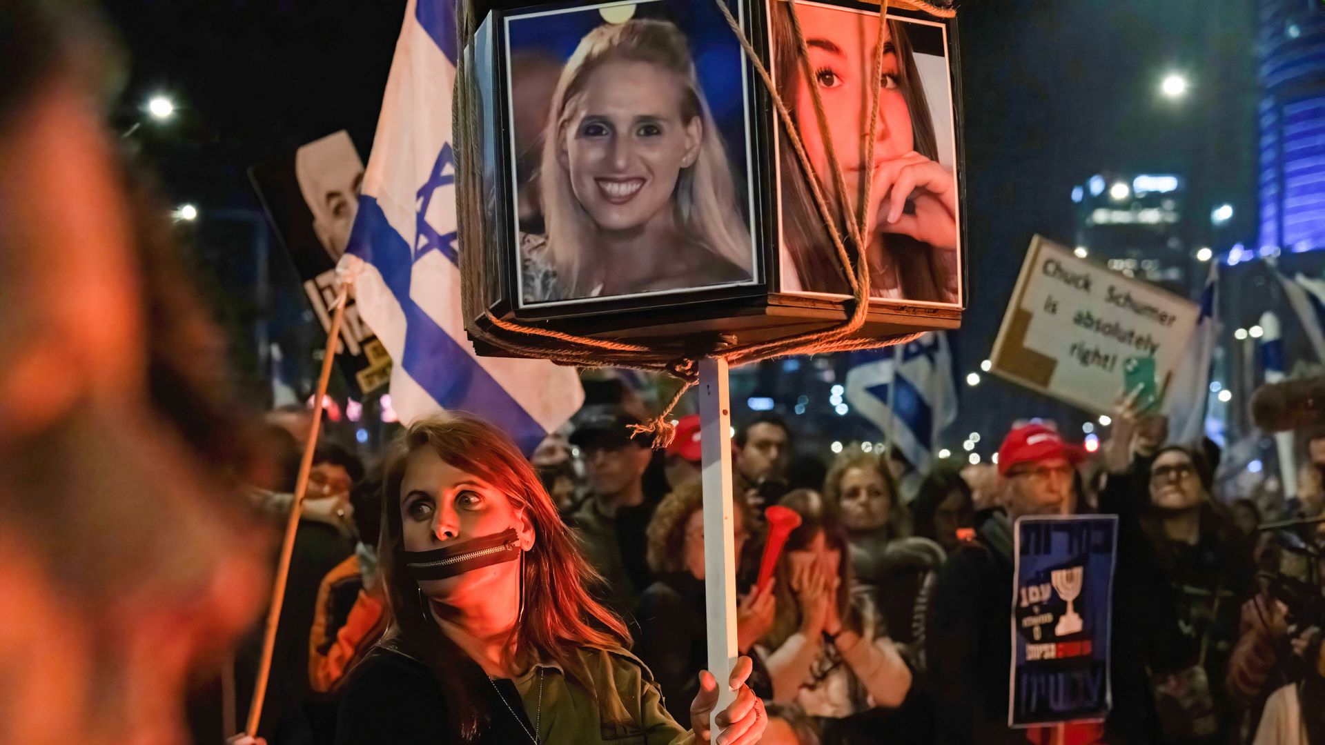A protester is seen wearing tape on her mouth, hands tied while carrying photos of women hostages during a demonstration on March 16, 2024