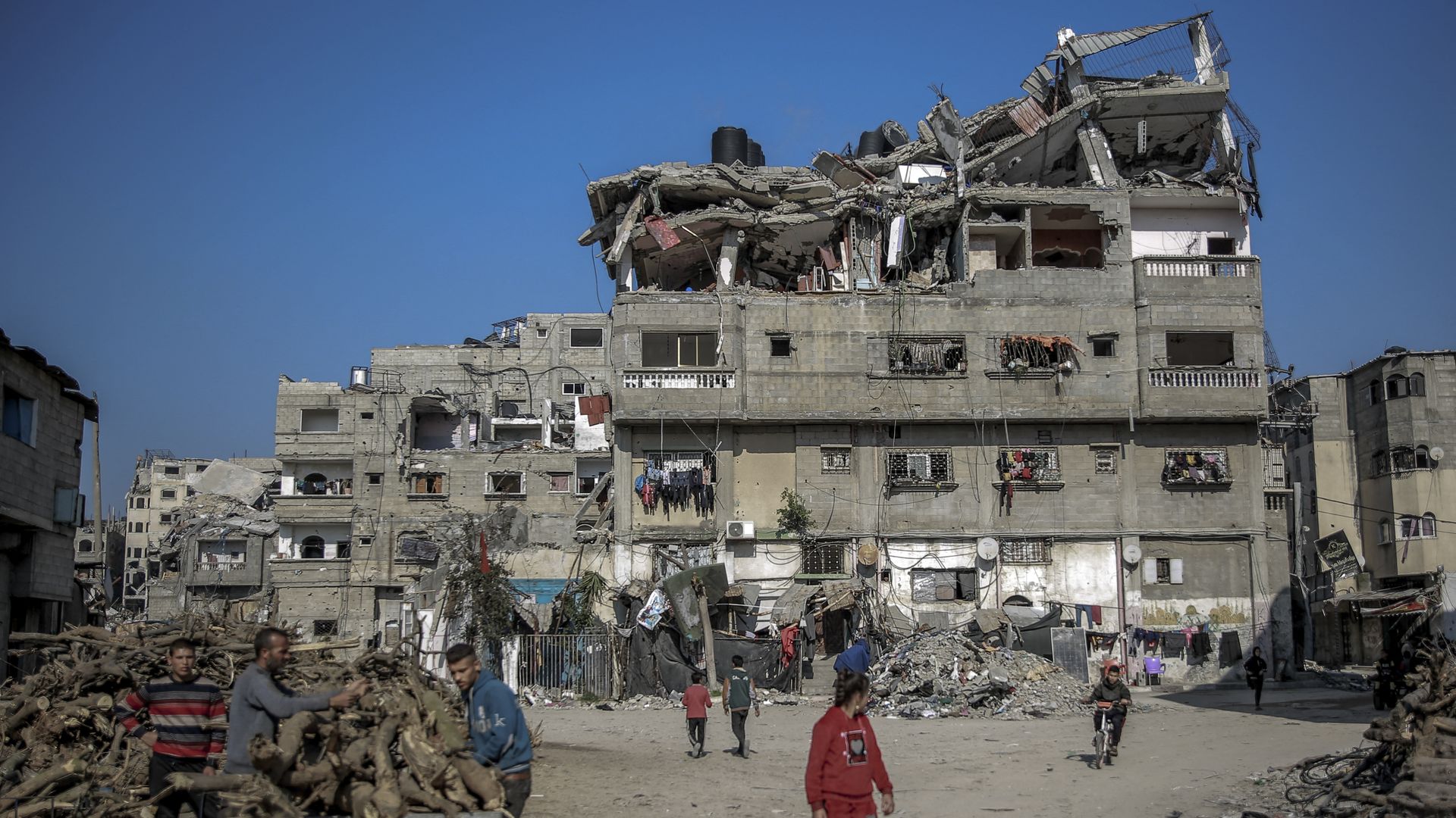 Palestinian men collect wood near a building destroyed during Israeli strikes in Beit Lahia in northern Gaza, on February 26, 2024, amid continuing battles between Israel and the Palestinian militant group Hamas. 