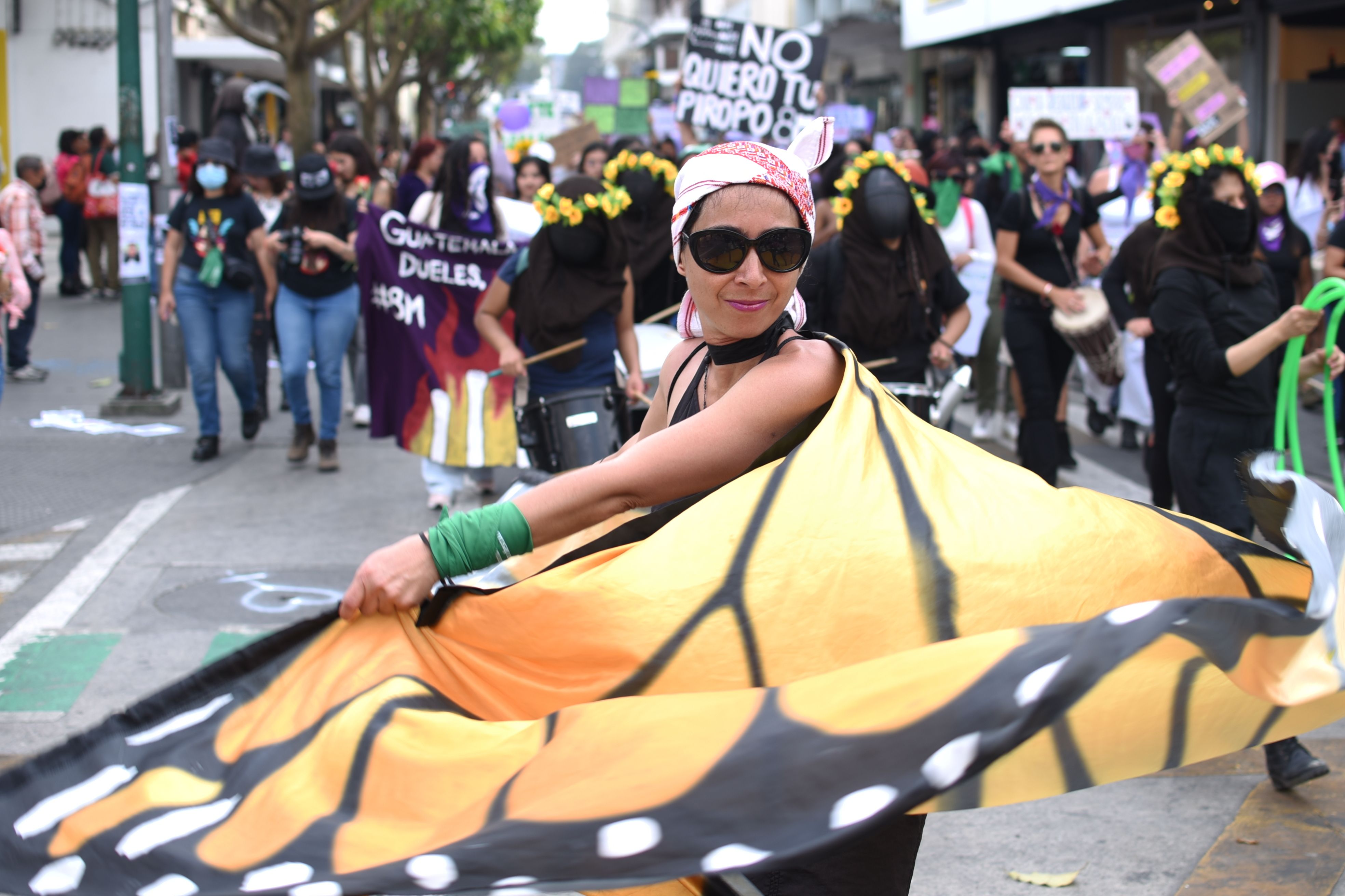 A woman swirls wearing a monarch butterfly cape while others march behind her during an International Women's Day protest in Guatemala City 
