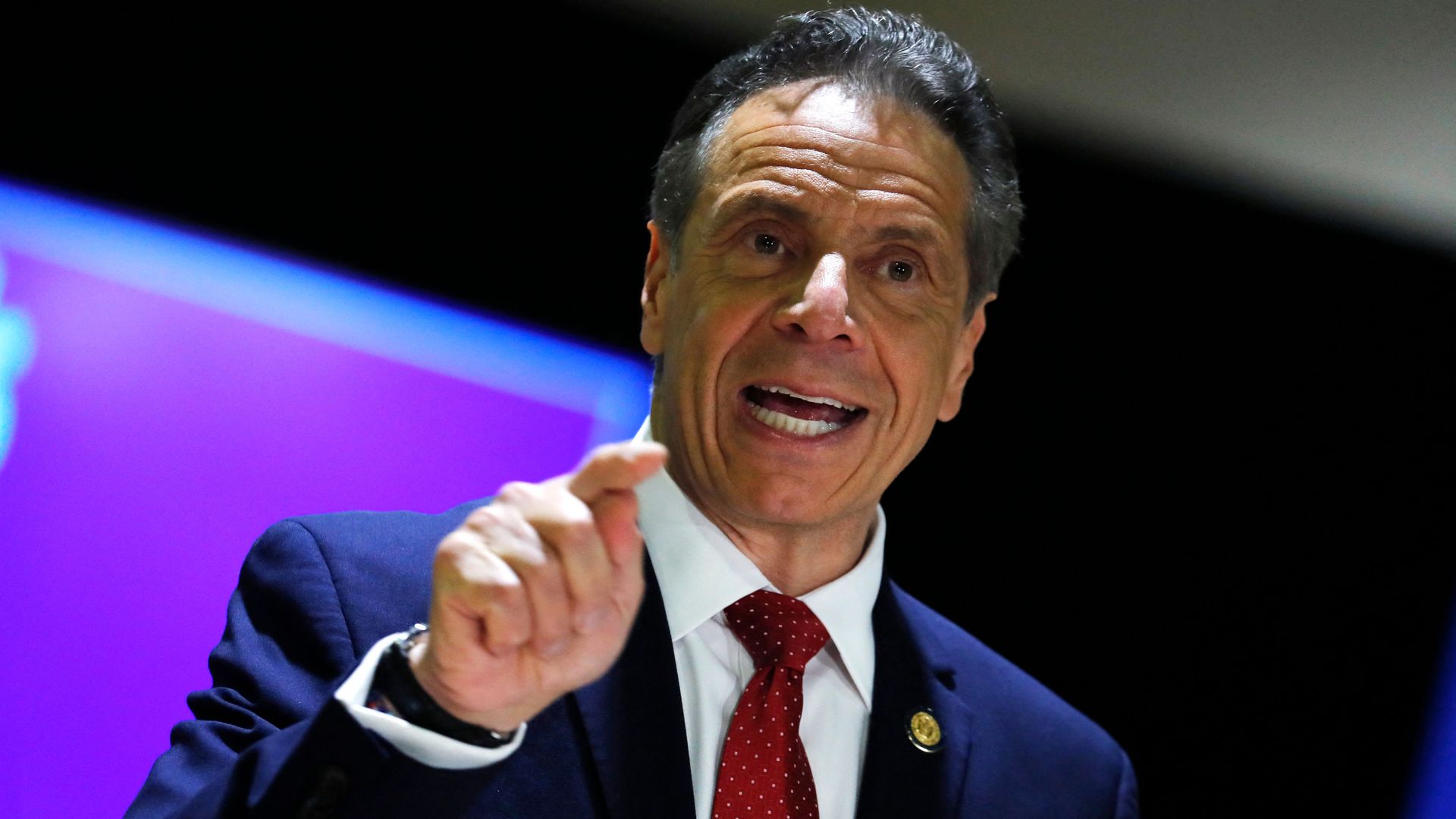 Cuomo points his index finger while wearing a suit