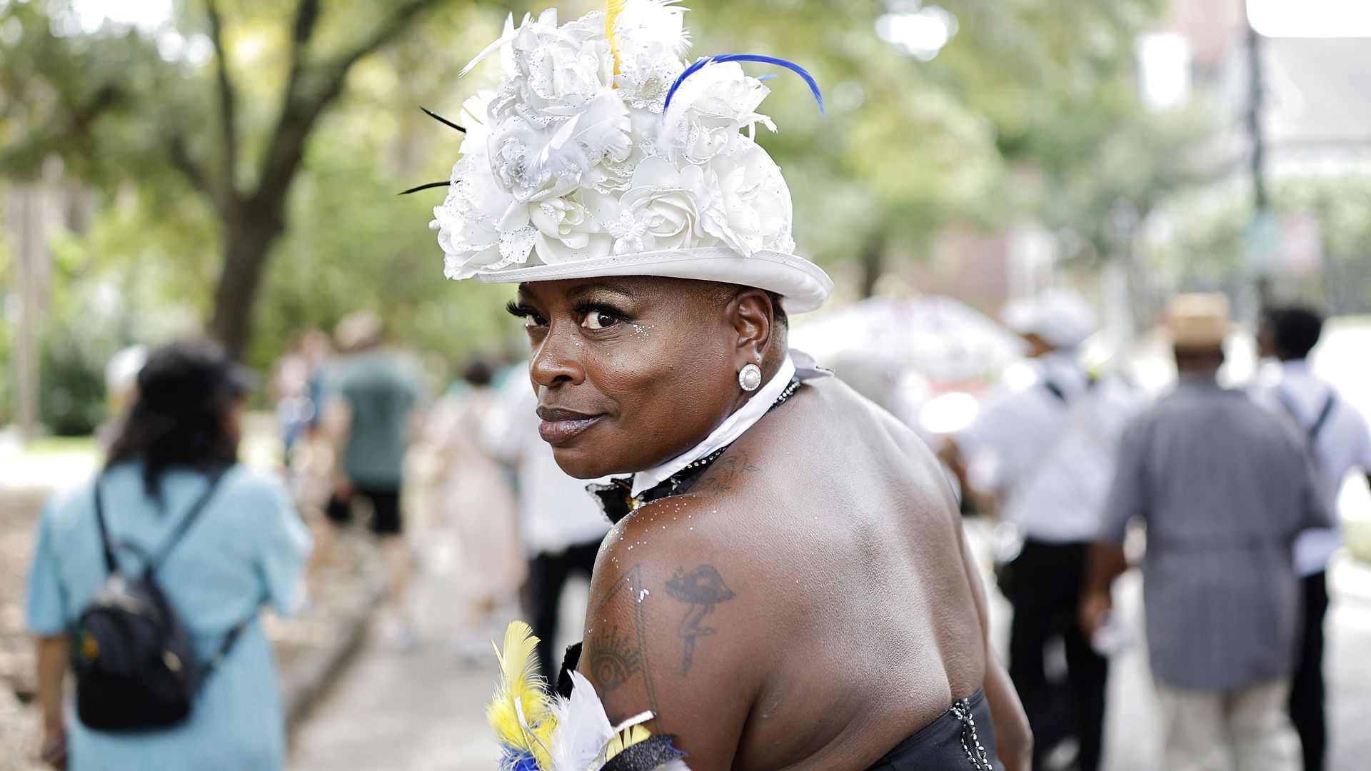A woman peers over her shoulder toward the camera as she walks in a street parade.