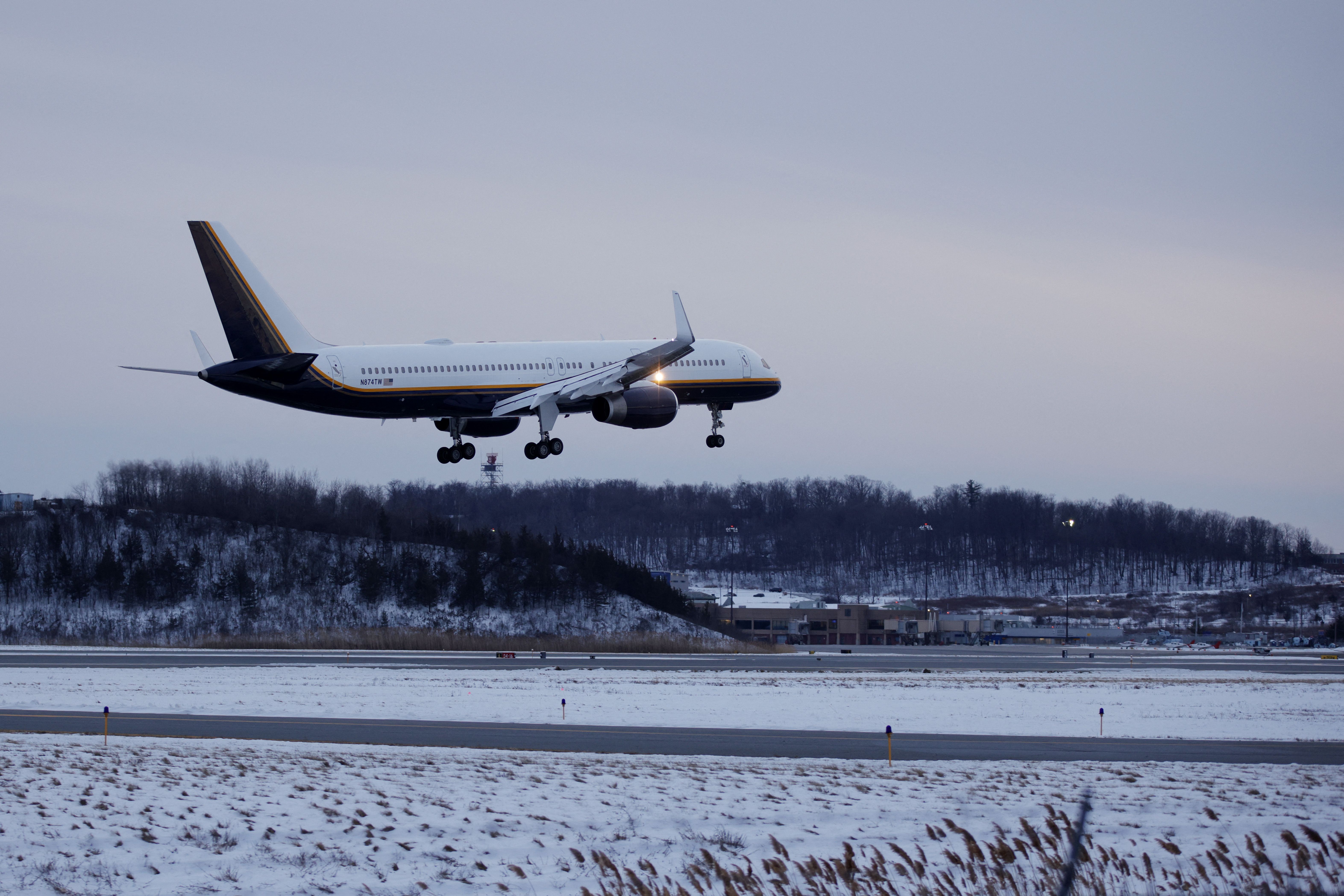 Plane about to land on runway on a snowy afternoon