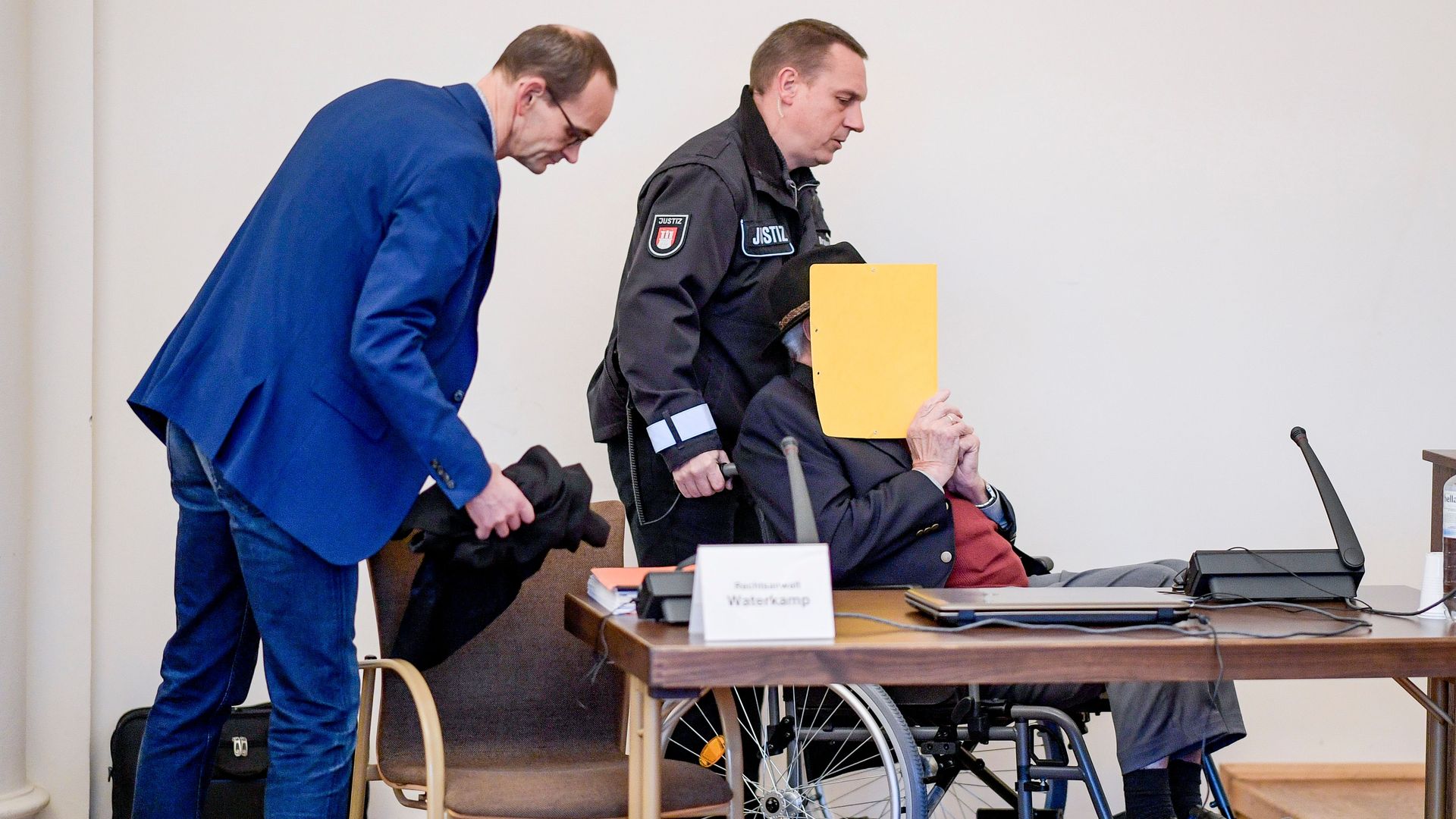 Bruno Dey covering his face with a folder.