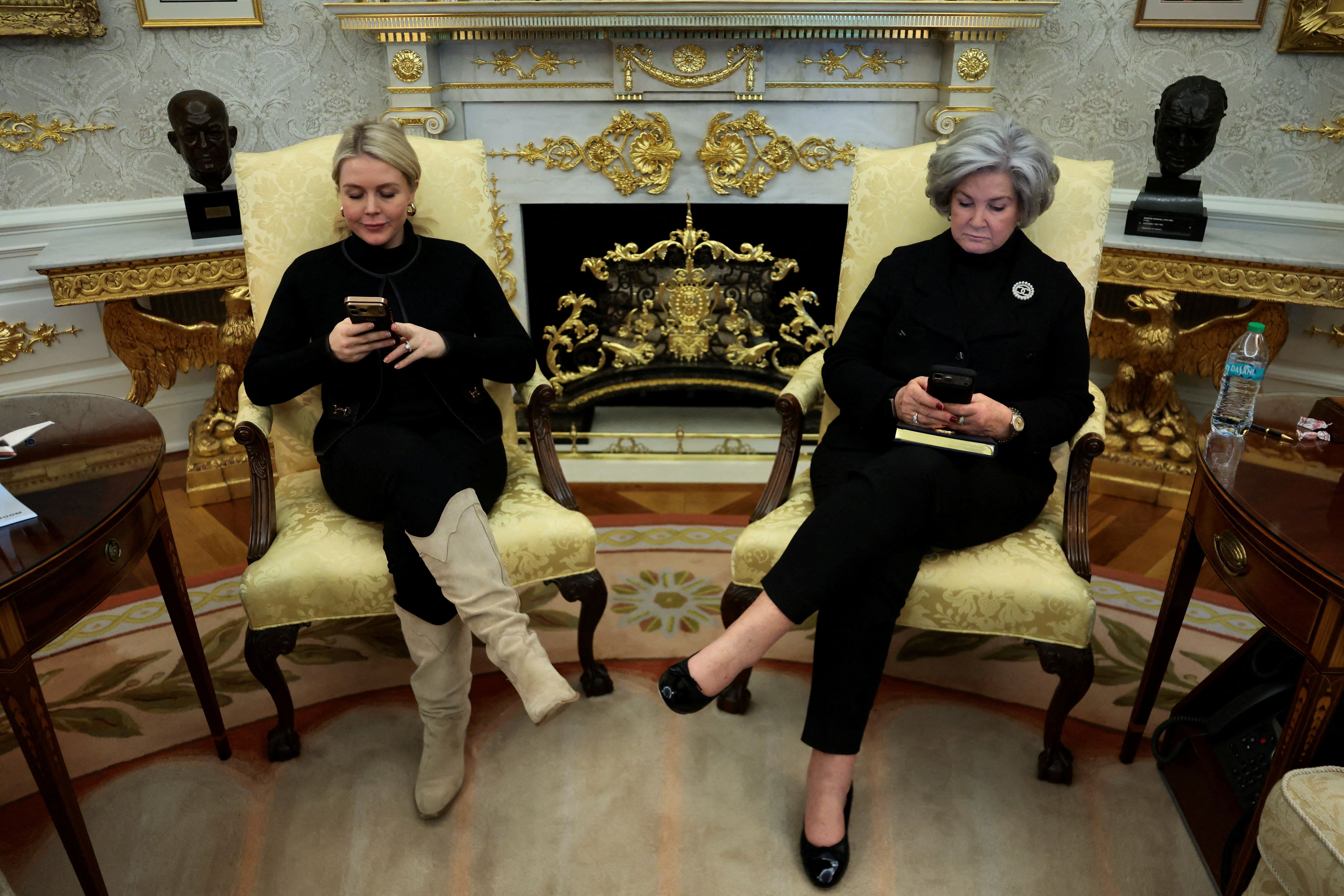 White House Press Secretary Karoline Leavitt and White House Chief of Staff Susie Wiles use their phones as President Trump announces the creation of a U.S. strategic reserve of critical minerals.