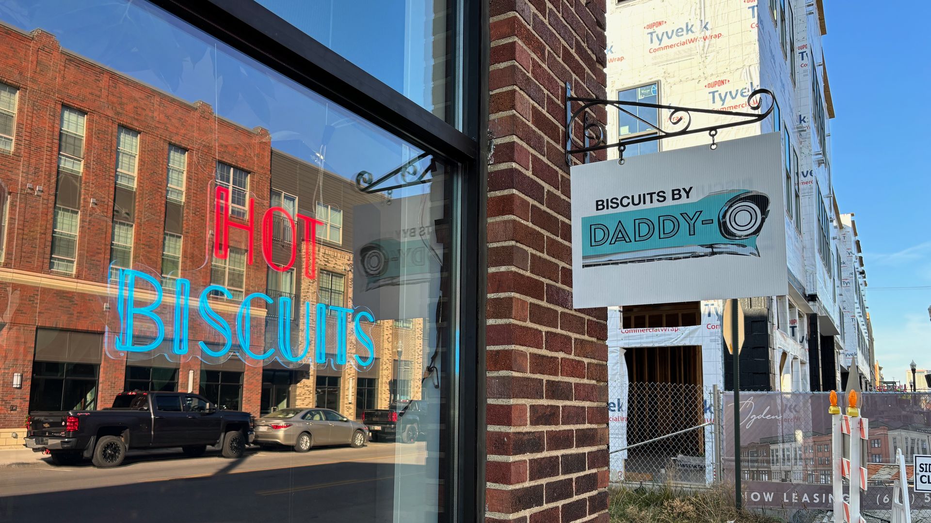 A neon sign reading "hot biscuits" on a window next to a "Biscuits By Daddy-O" sign.