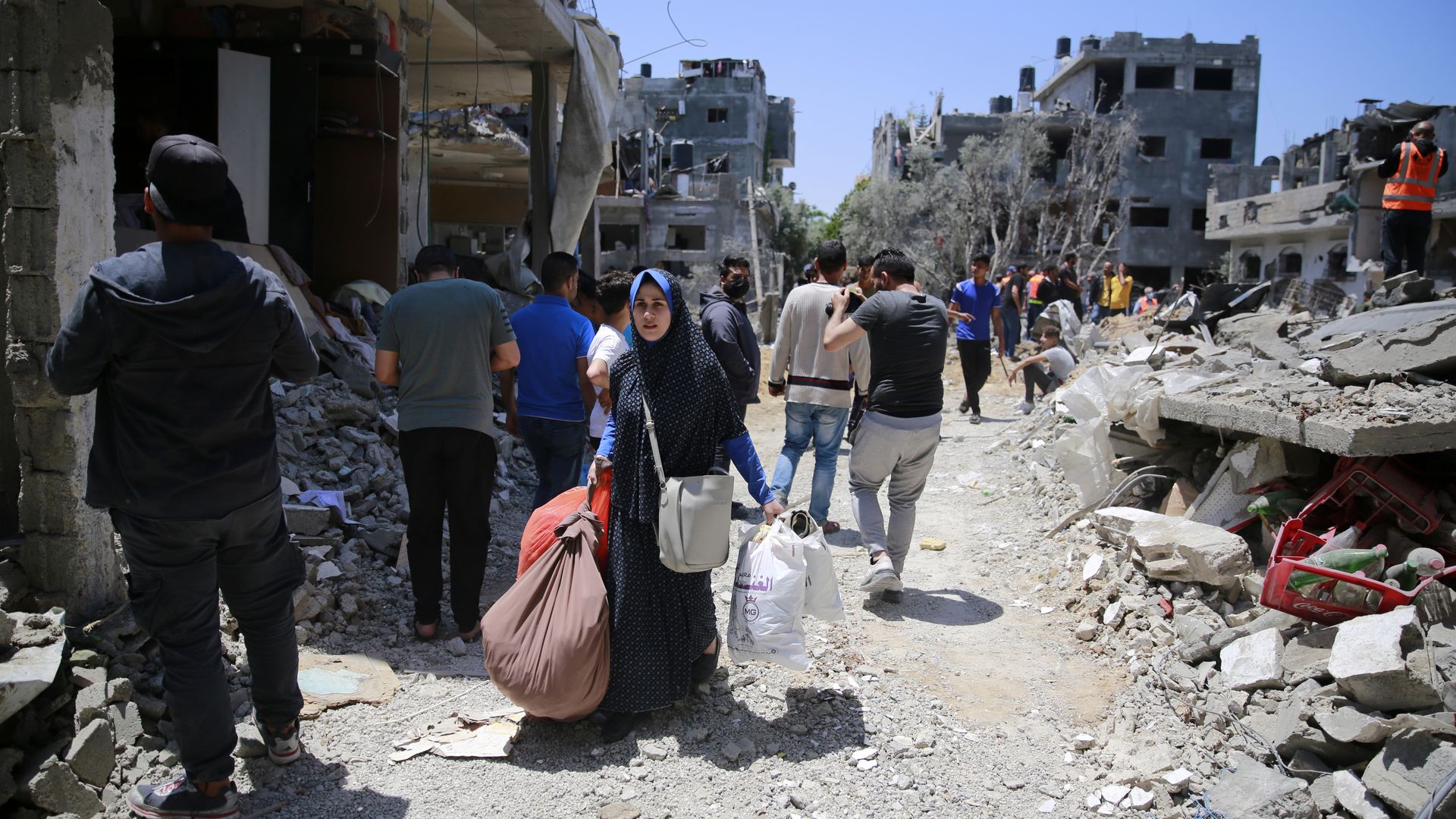 A Palestinian woman walks as she collects her belongings inside her damaged house in the aftermath of Israeli air and artillery strikes as cross-border violence in the Gaza Strip.