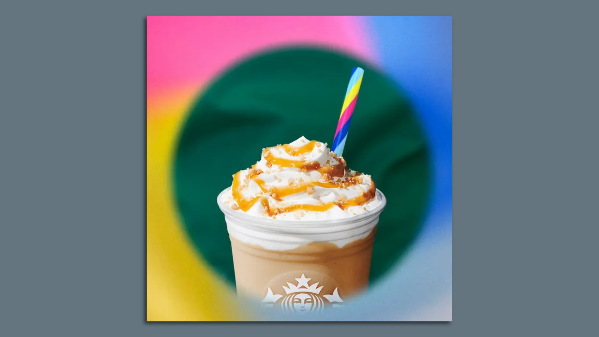 Gray background with square and top of Starbucks cup with whipped cream and caramel drizzle and a multi-colored reusable straw 