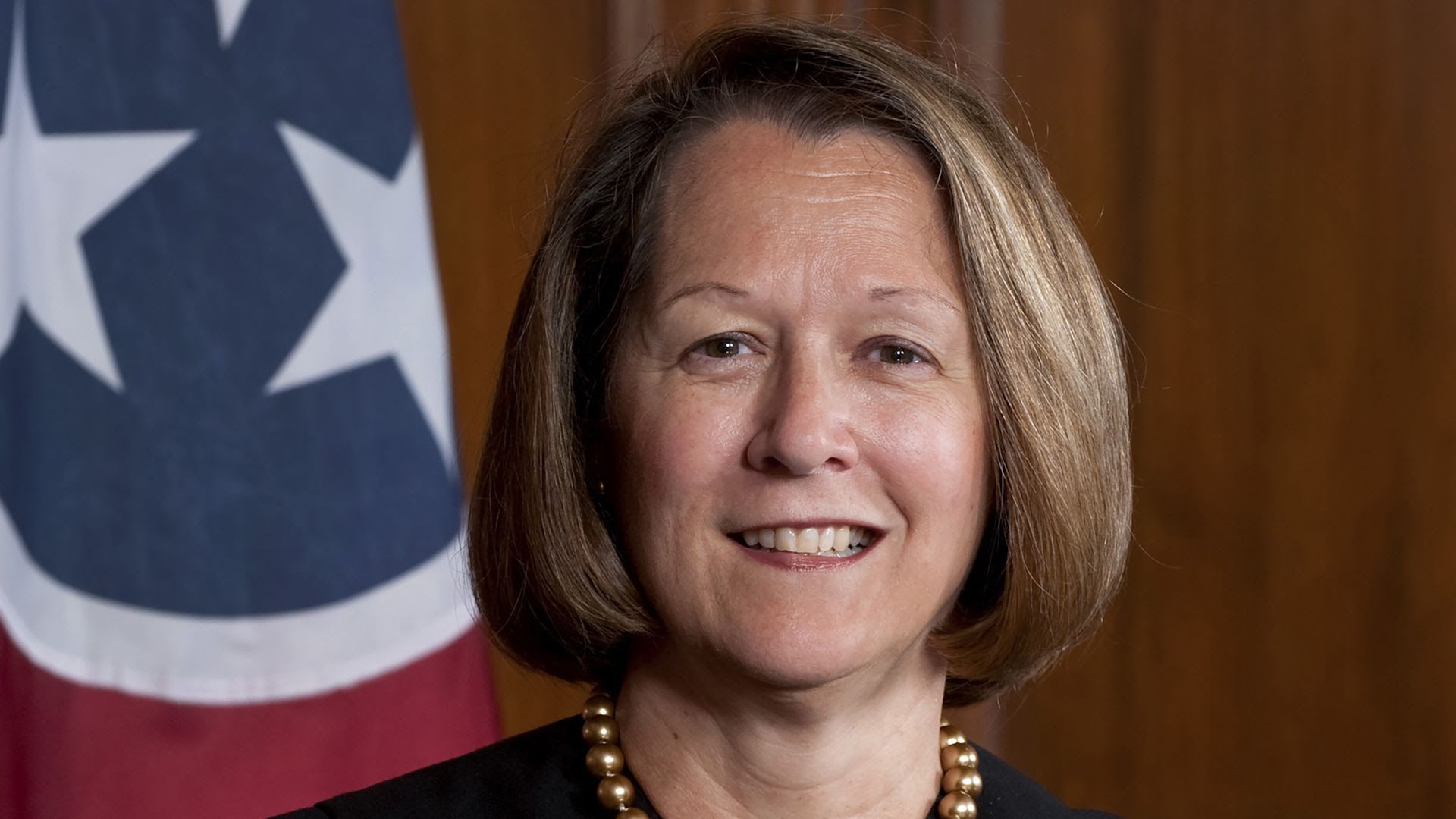 A portrait of the late Justice Cornelia Clark in front of a Tennessee state flag.