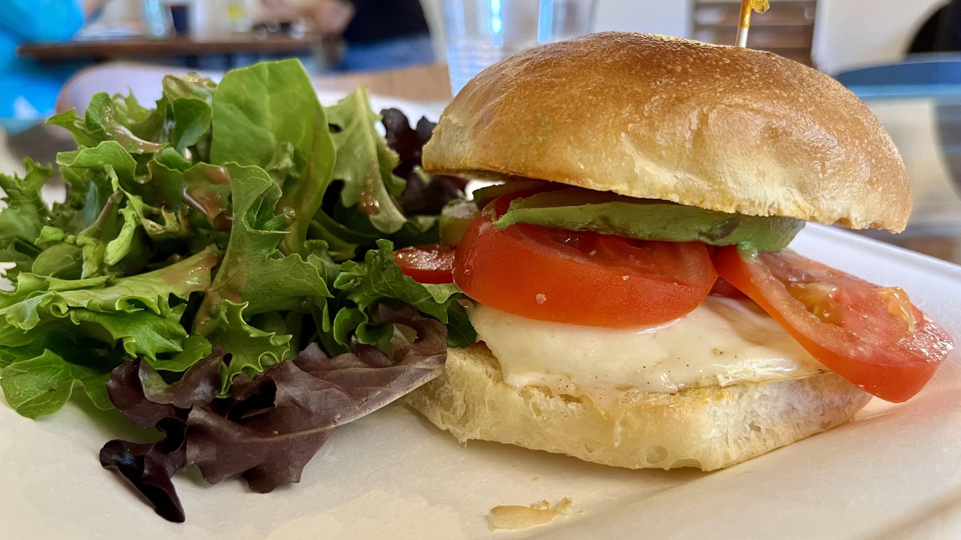 A brioche sandwich with egg, tomato and a side salad. 