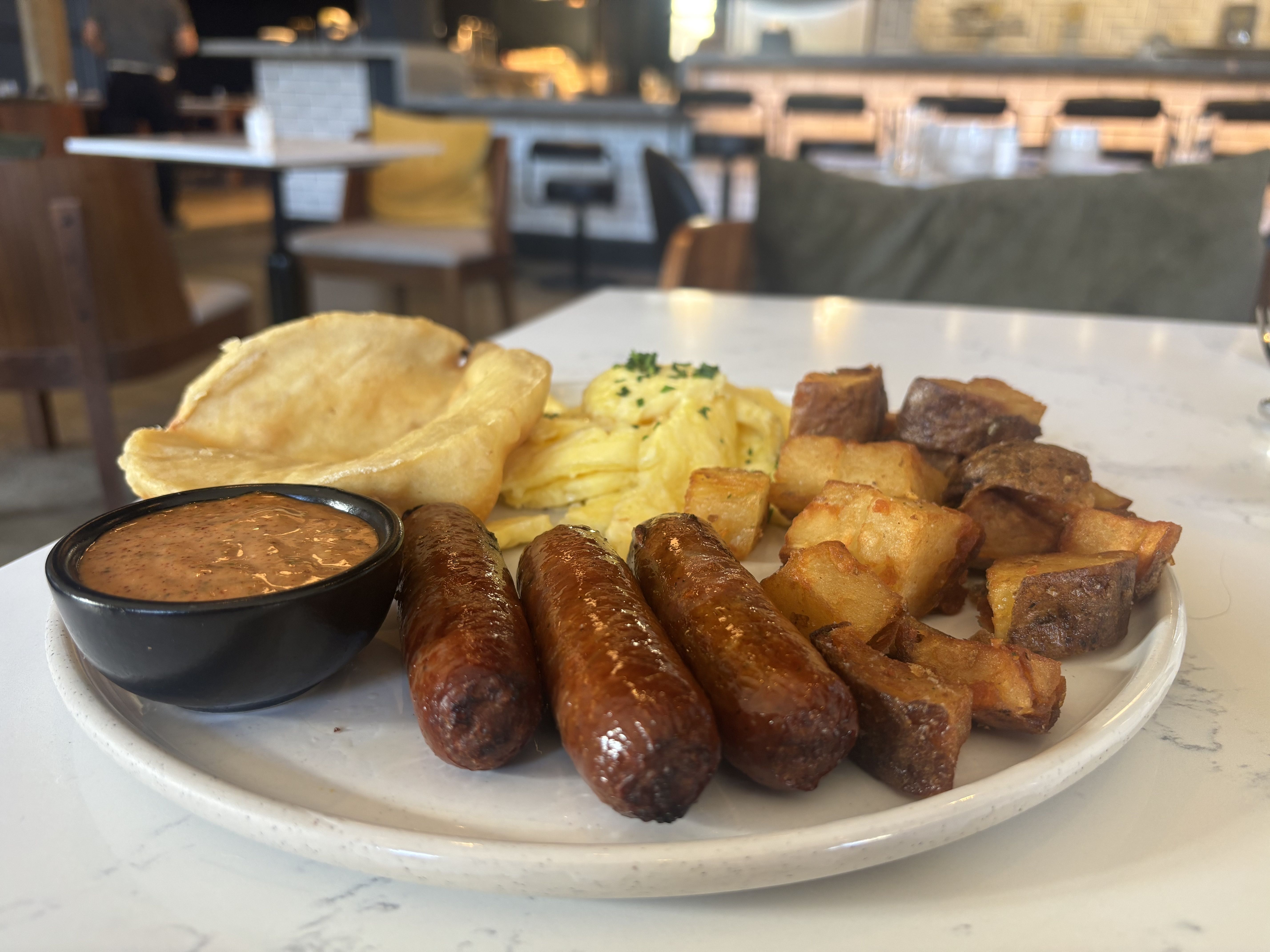 Breakfast including eggs, sausage, potatoes and fry bread.
