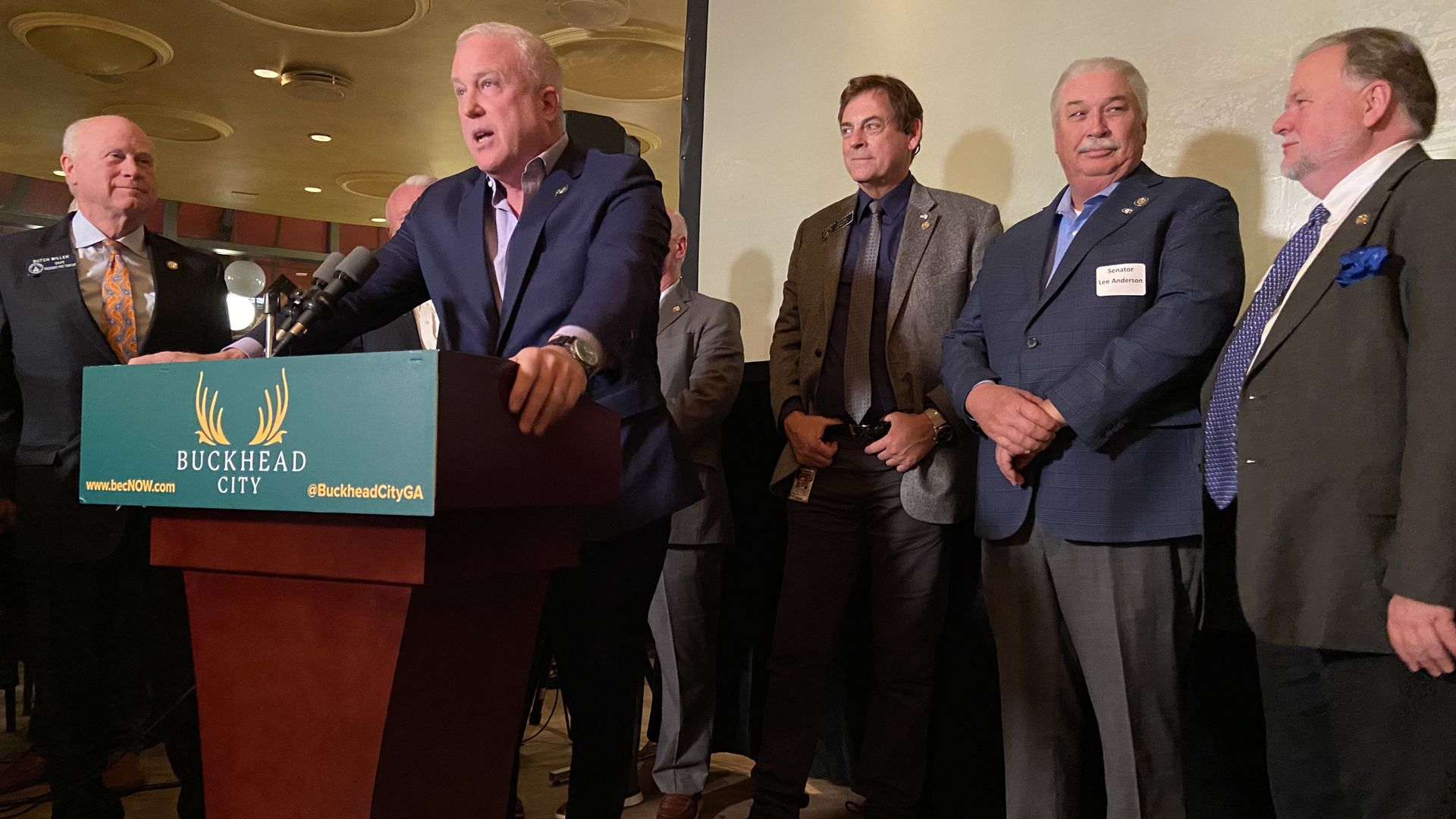 Man at podium surrounded by other men
