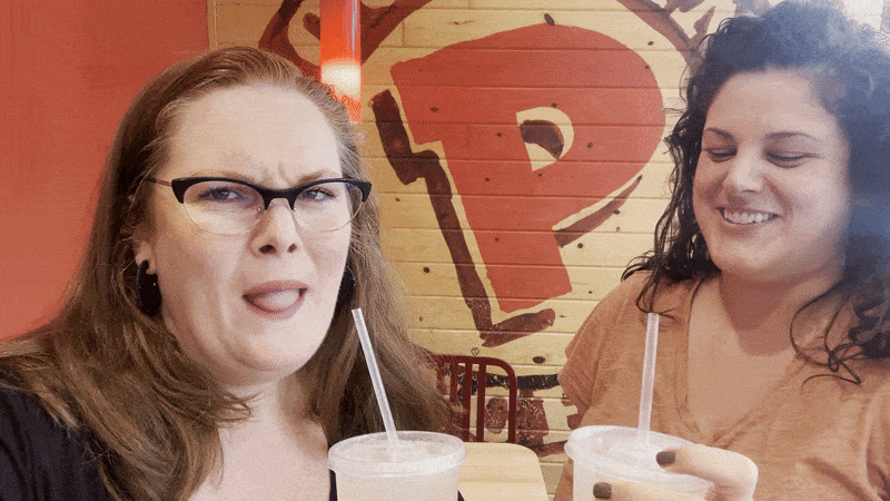 Photo shows two women making icky faces with a drink.