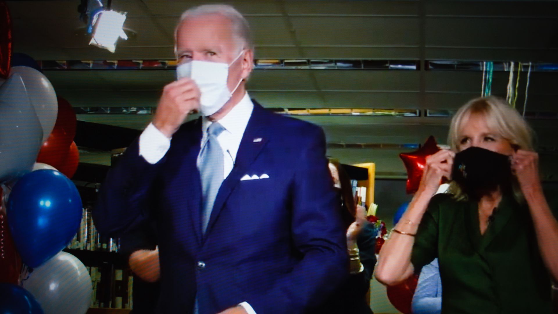 Biden and his wife walk through a hall while masking up at the Democratic National Convention.