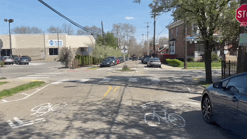 Riding a bike around a small roundabout on a quite, tree-lined side street