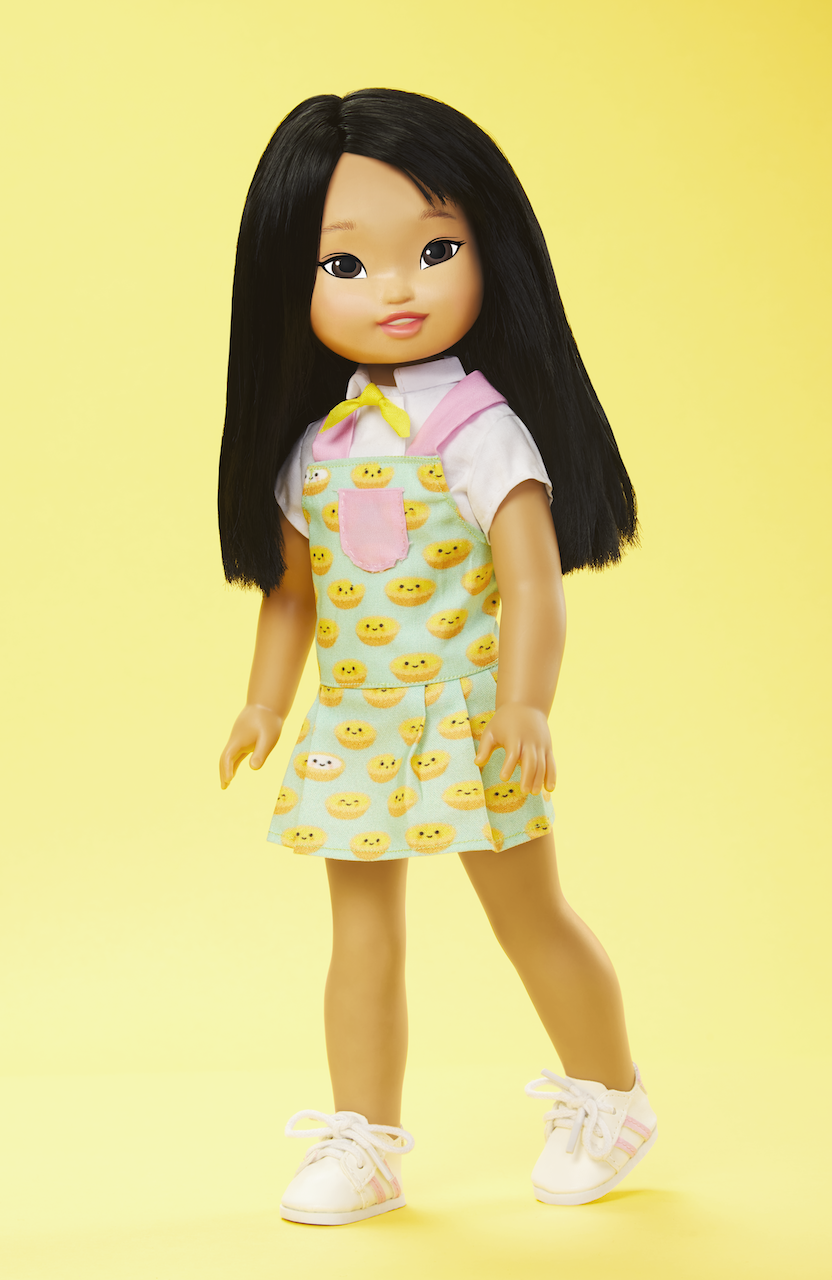 Photo of an Asian American girl doll wearing a colorful apron and looking at the camera