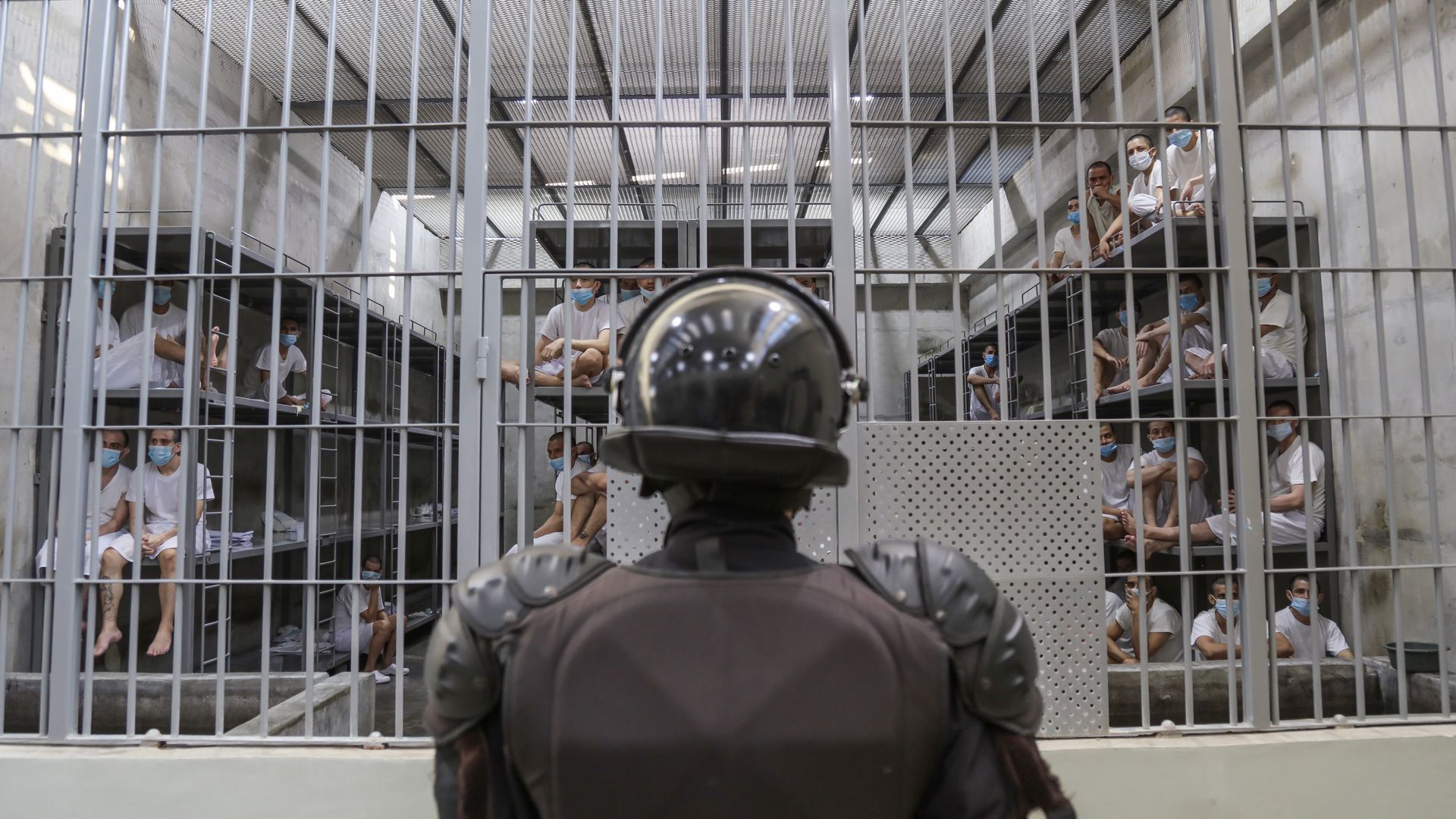 A guard watches over men in a massive cell in a Salvadoran megaprison.