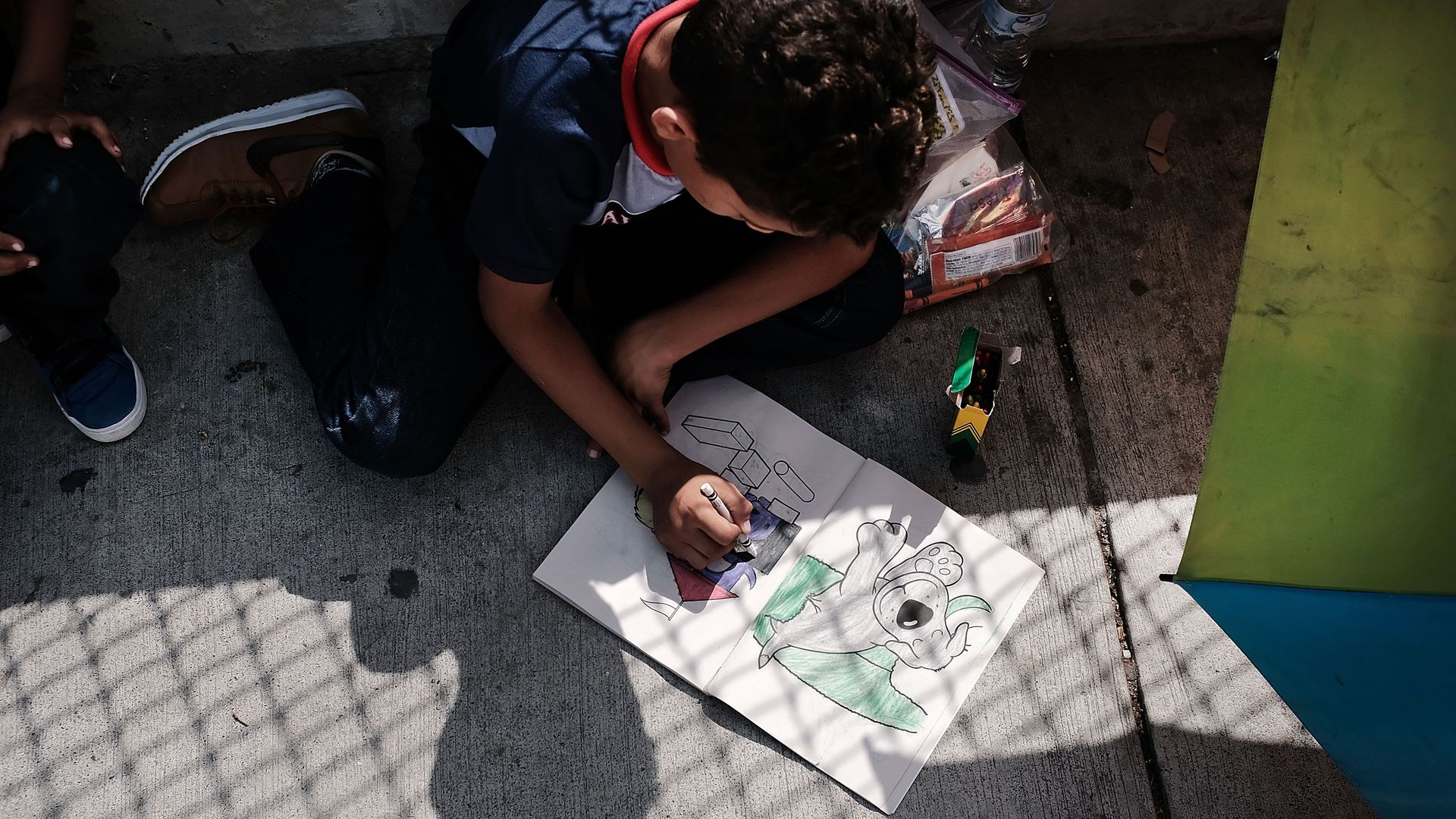 A migrant child colors at the border
