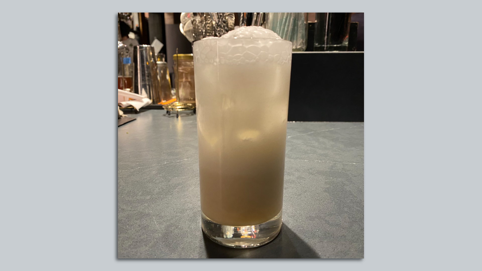 A photo of a frosty drink in a tall glass on a granite bar. 