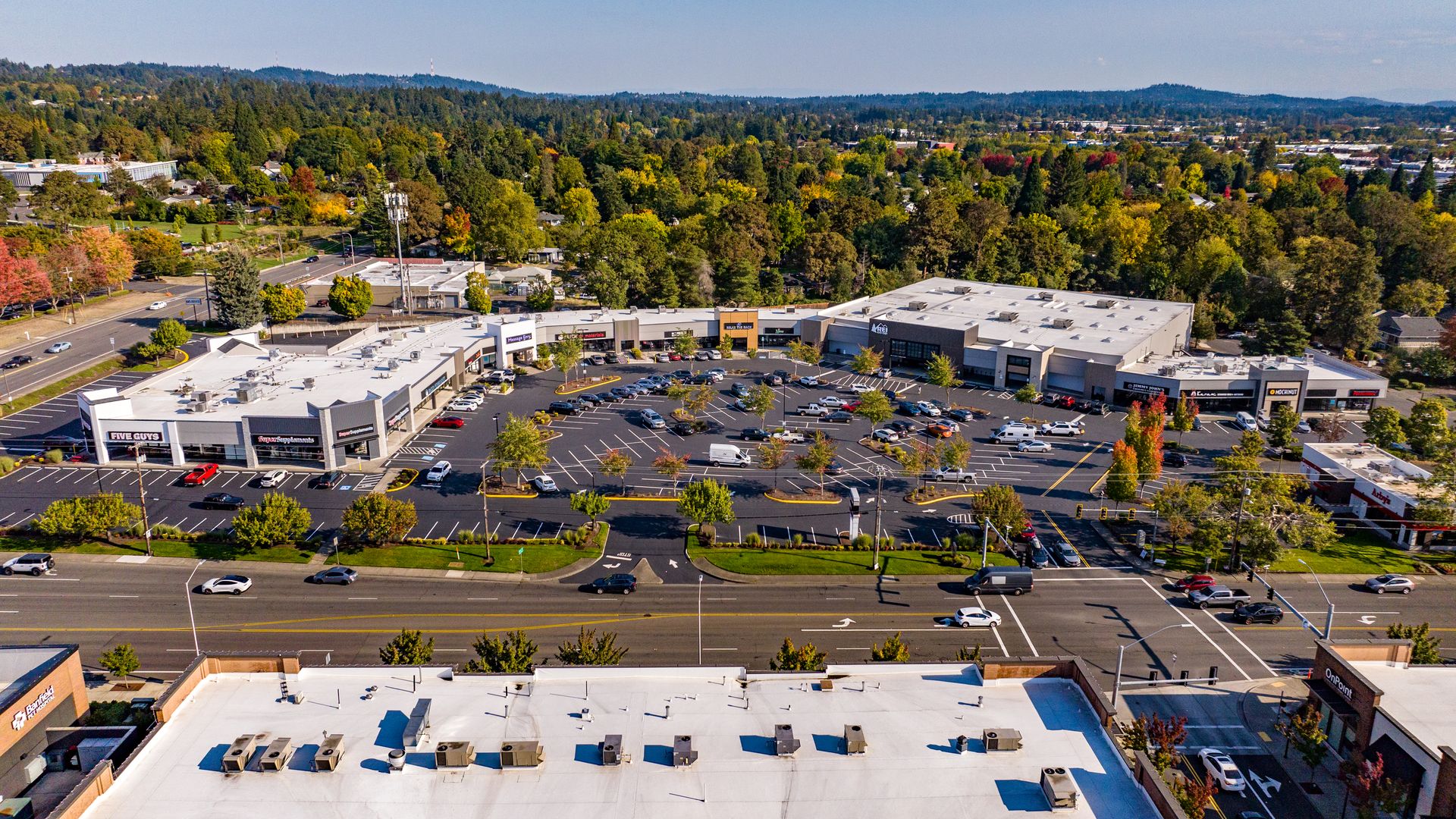 Aerial view of Walker Place shopping center featuring retail stores, restaurants and a large parking lot surrounded by trees and roads.