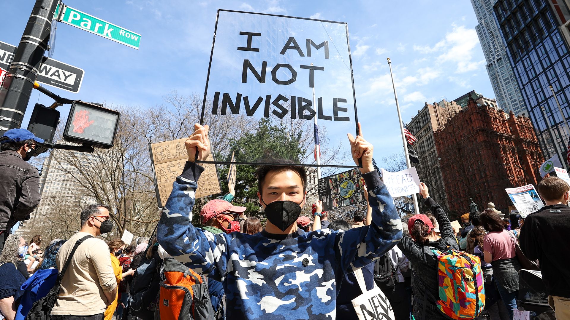 Photo of a protester holding a sign that says "I am not invisible"