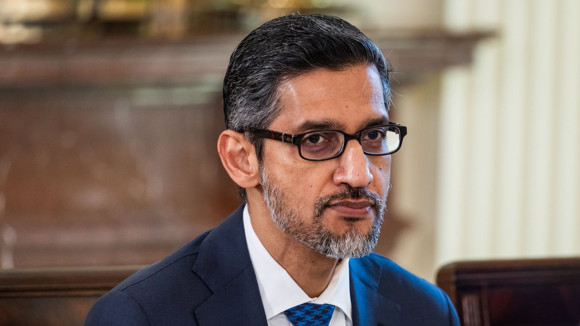 Google CEO Sundar Pichai, in a suit and blue checked tie, seated at the White House. 
