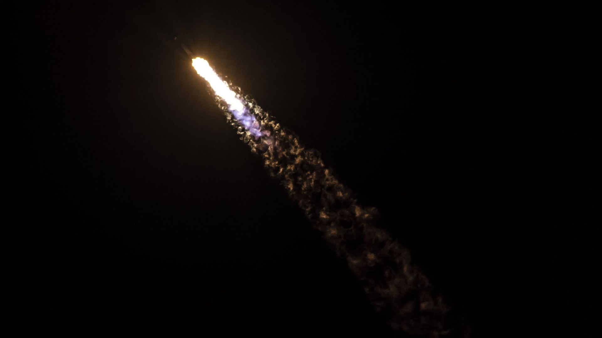 A SpaceX rocket launch at night.