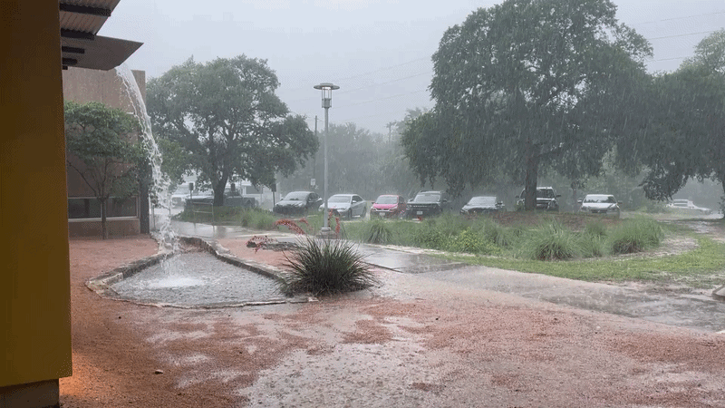 Heavy rain falls in front of a parking lot.