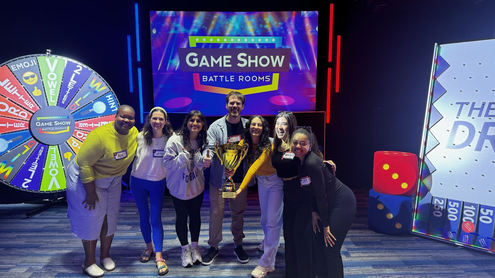 Axios teammates hold a trophy at Game Show Battle Rooms. 