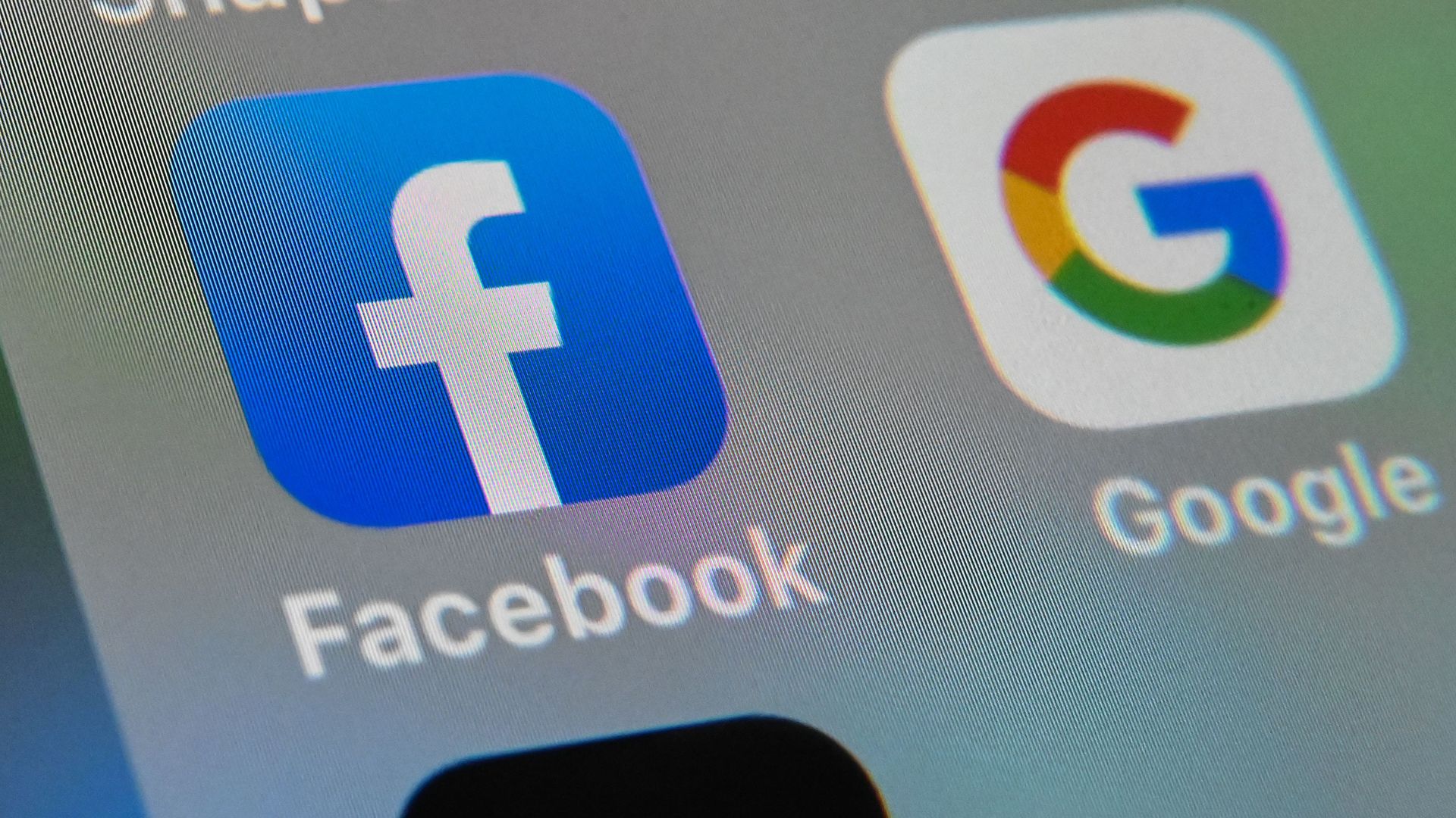 A photo of the Facebook and Google mobile app logos on a tablet screen.