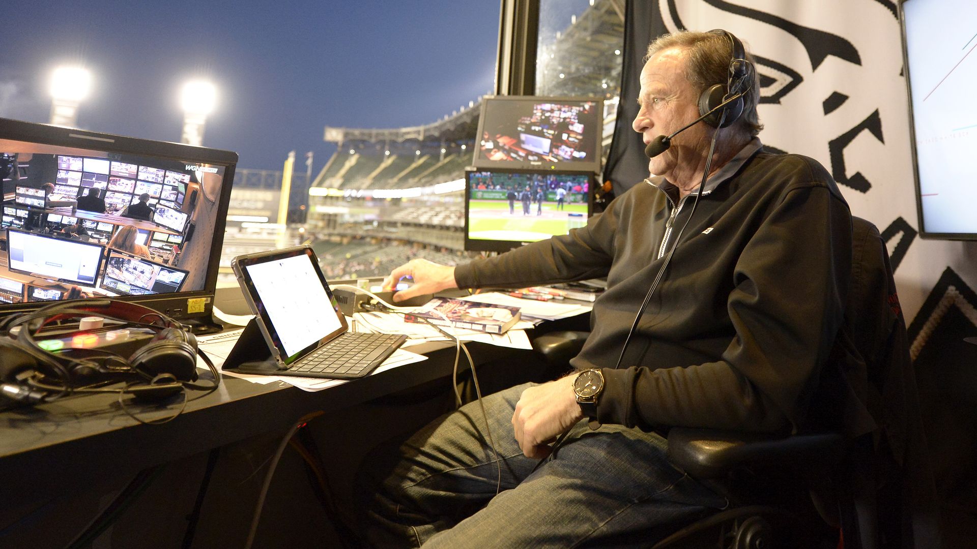 Photo of a man broadcasting with a headset microphone inside a stadium 