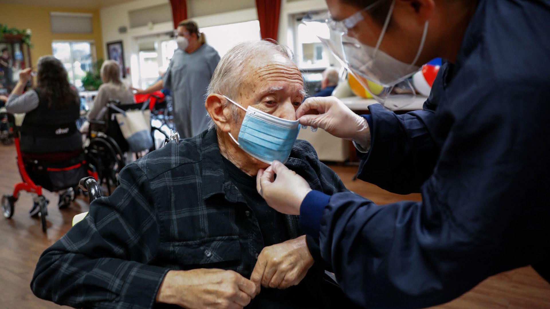 Image of a mask being put on an elderly man in a nursing home.