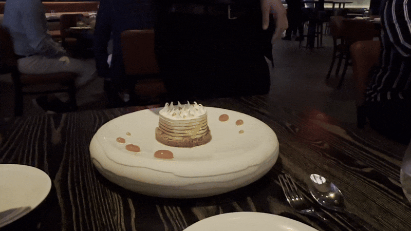 A server pours flaming bourbon onto a dessert plate.