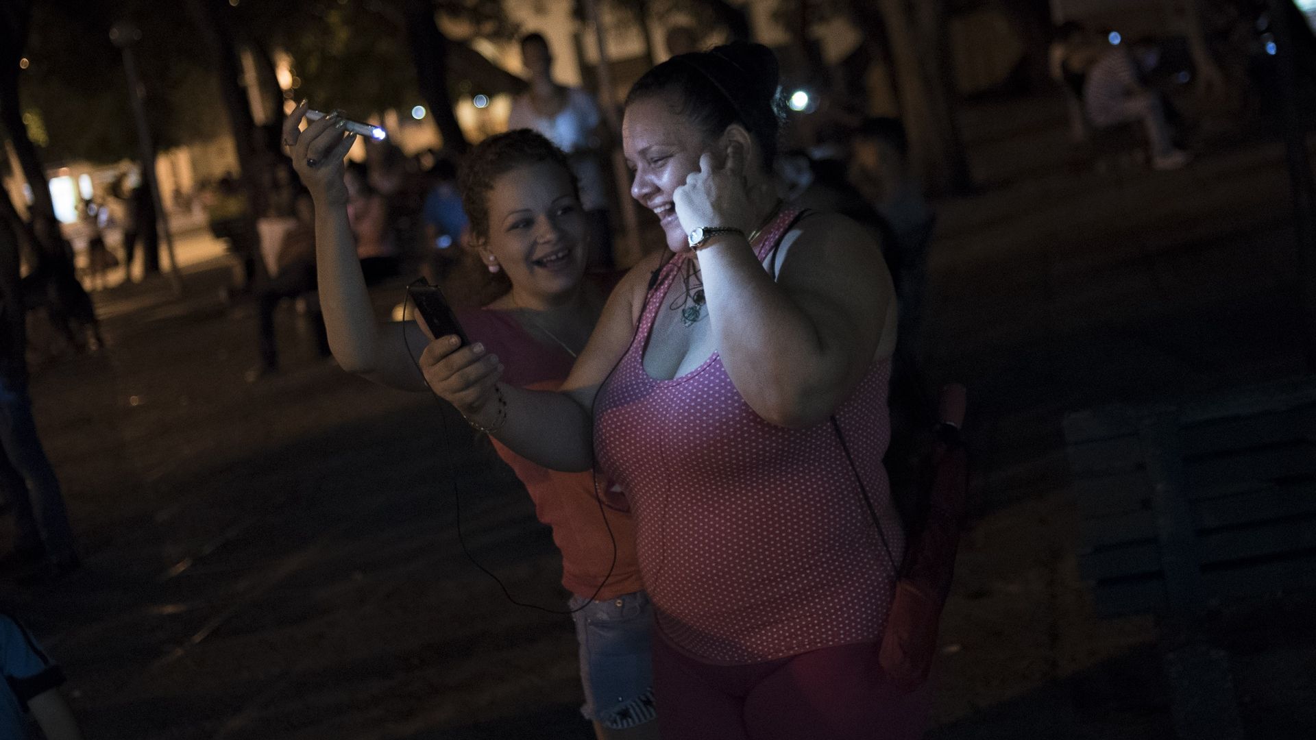 A Cuban woman uses her mobile phones to connect to the internet and speak with her relatives abroad