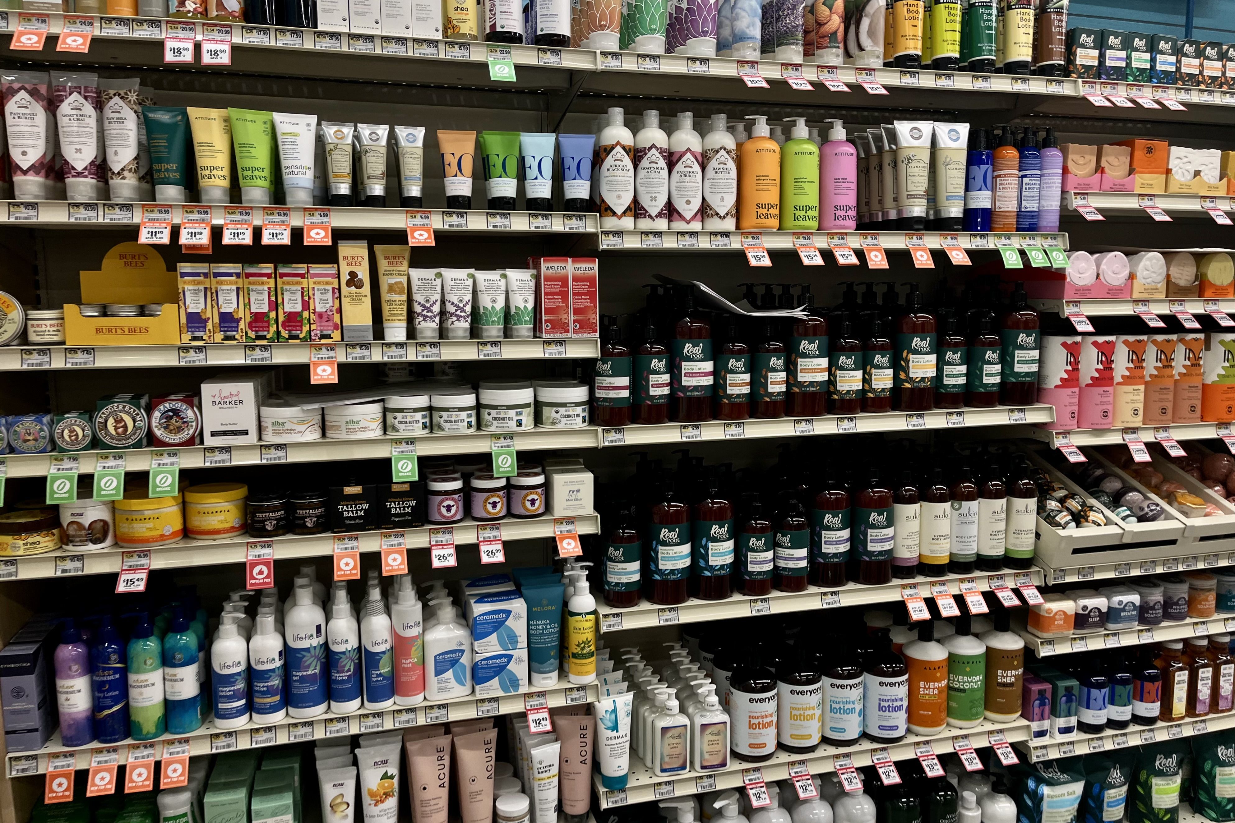 Store shelves stocked with various skincare and body lotion products in colorful packaging, including brands like Burt's Bees.