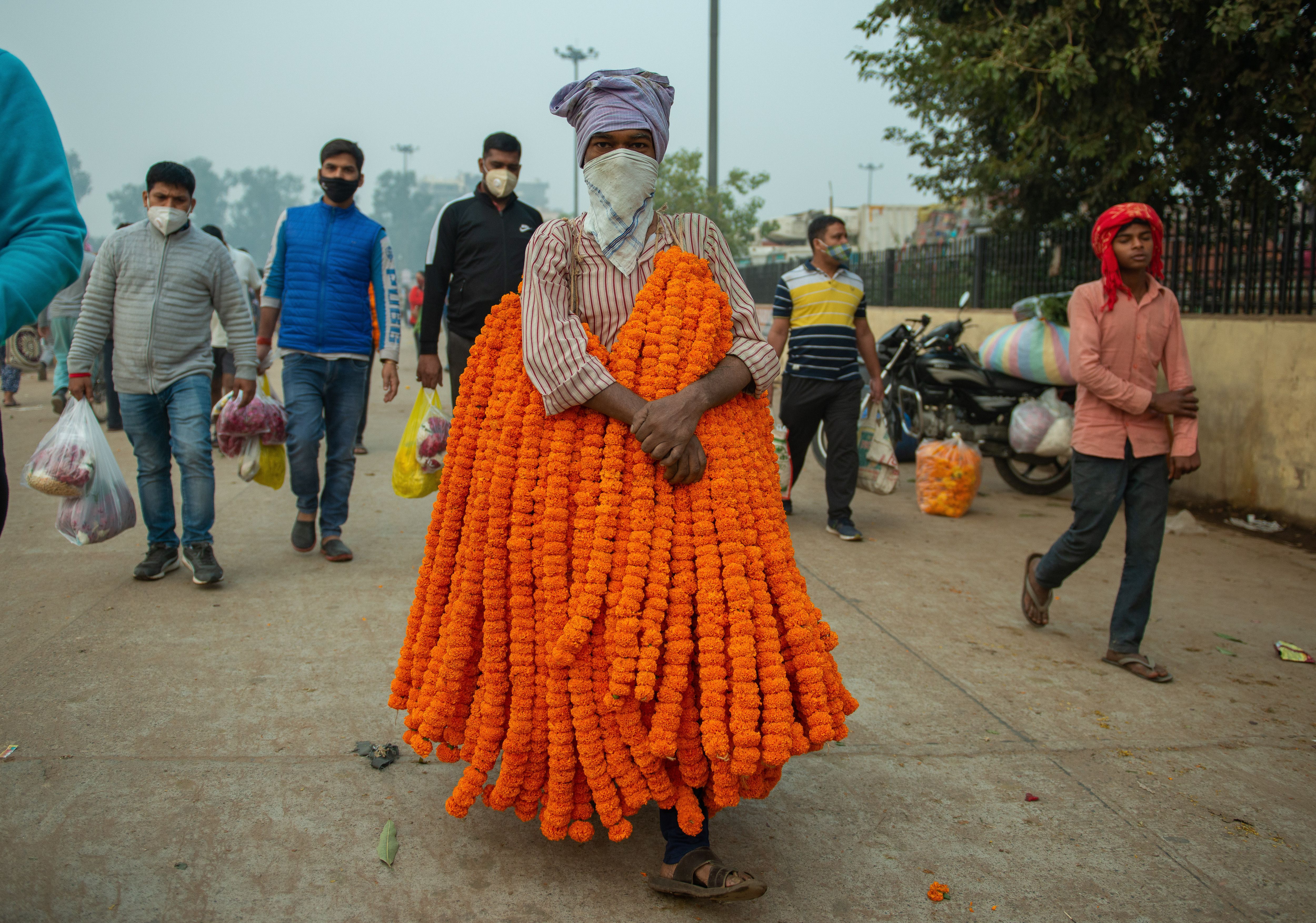 A man is seen carrying marigold flower garlands for sale for Diwali in the flower market in New Delhi, India