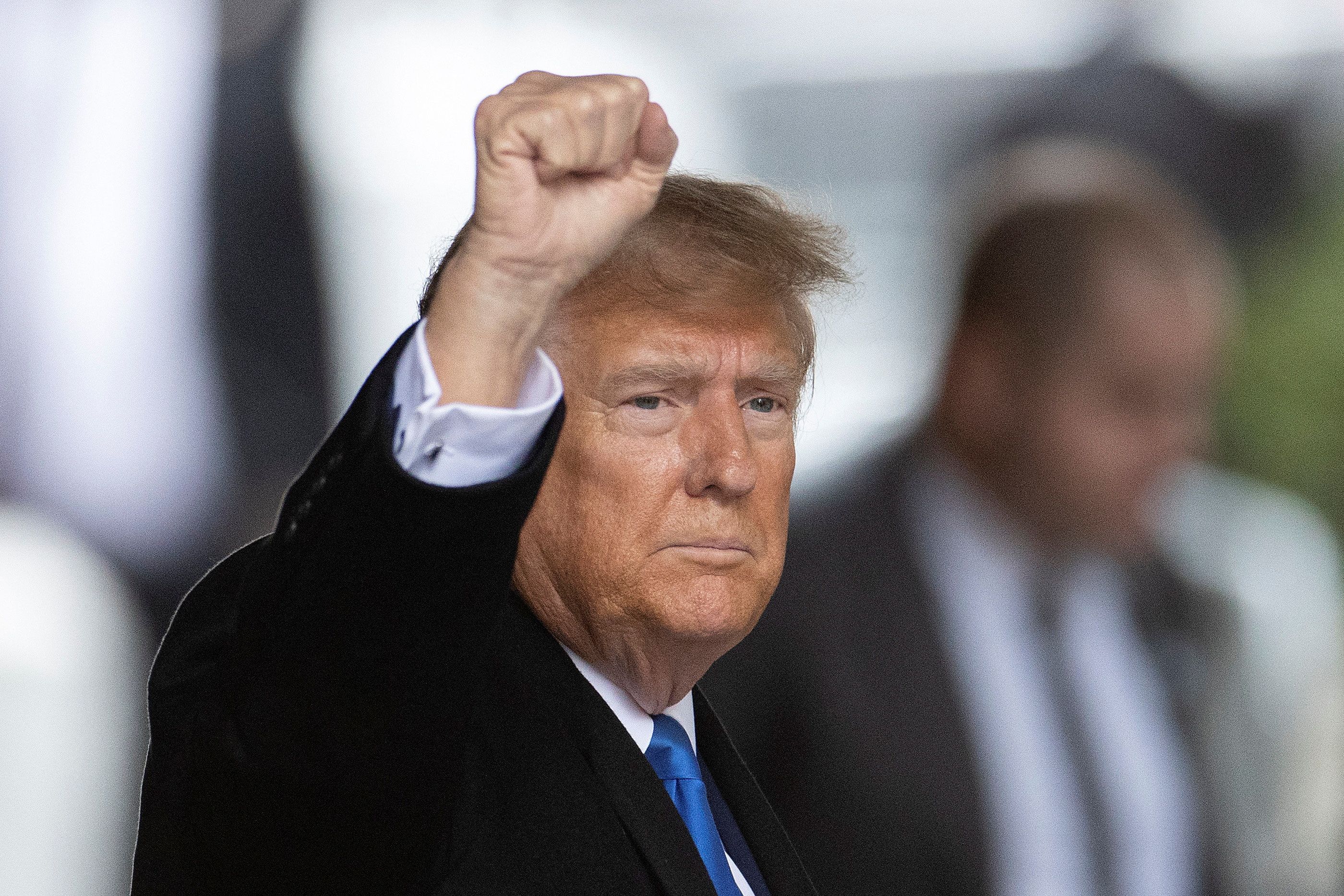 Former President Trump raises his fist before briefly taking the stand at a defamation trial brought by writer E. Jean Carroll.
