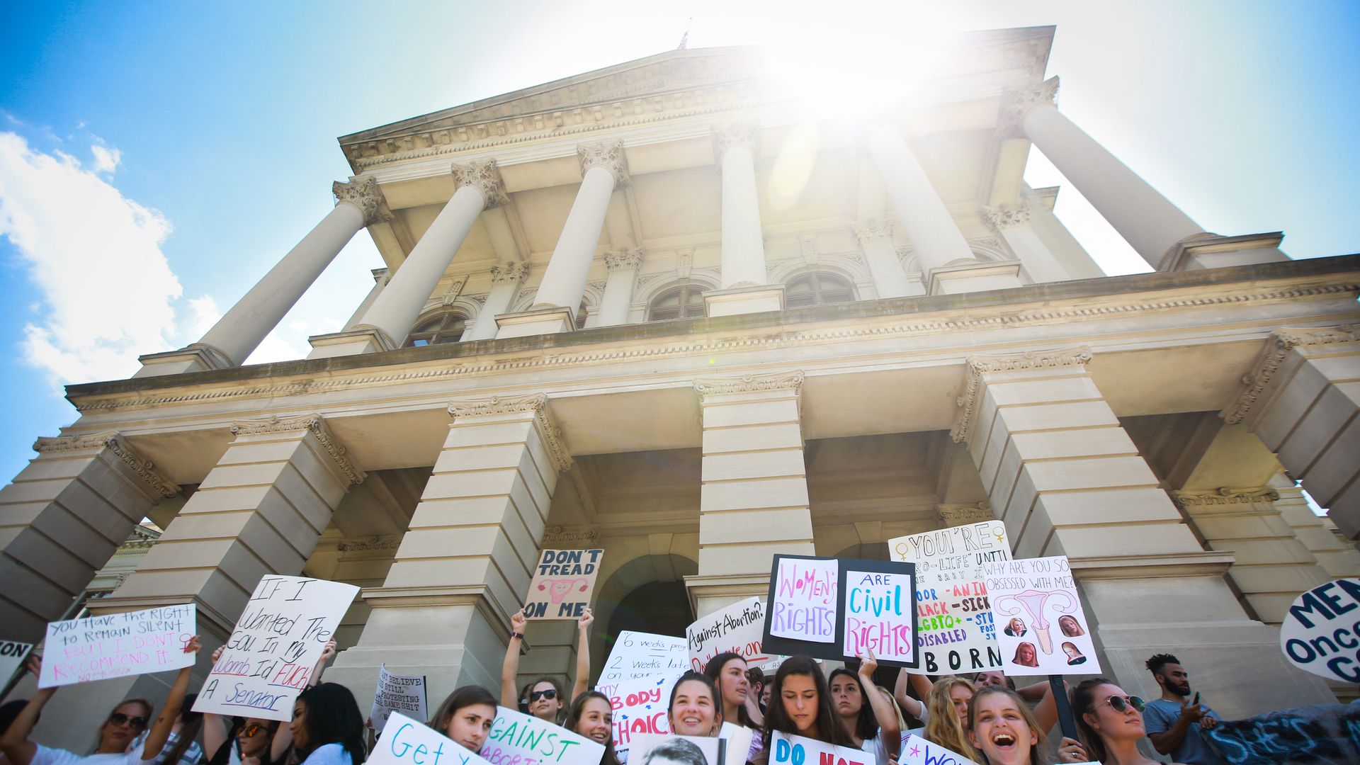 In this image, a group of mostly women hold protests signs, some of which read: "I have a right to privacy" and "get your creepy hands off my rights."