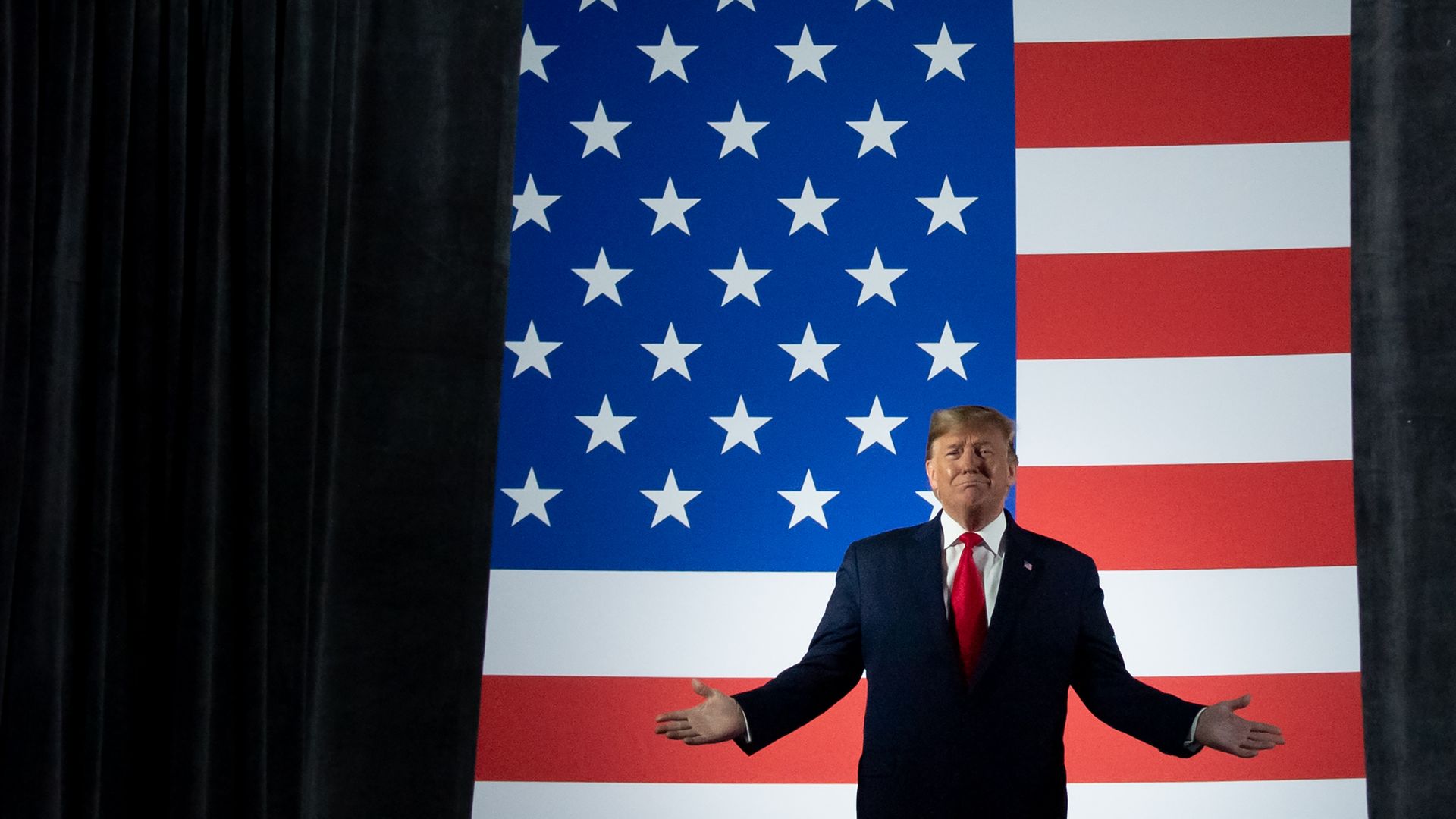 In this image, Trump stands with the American flag behind him.