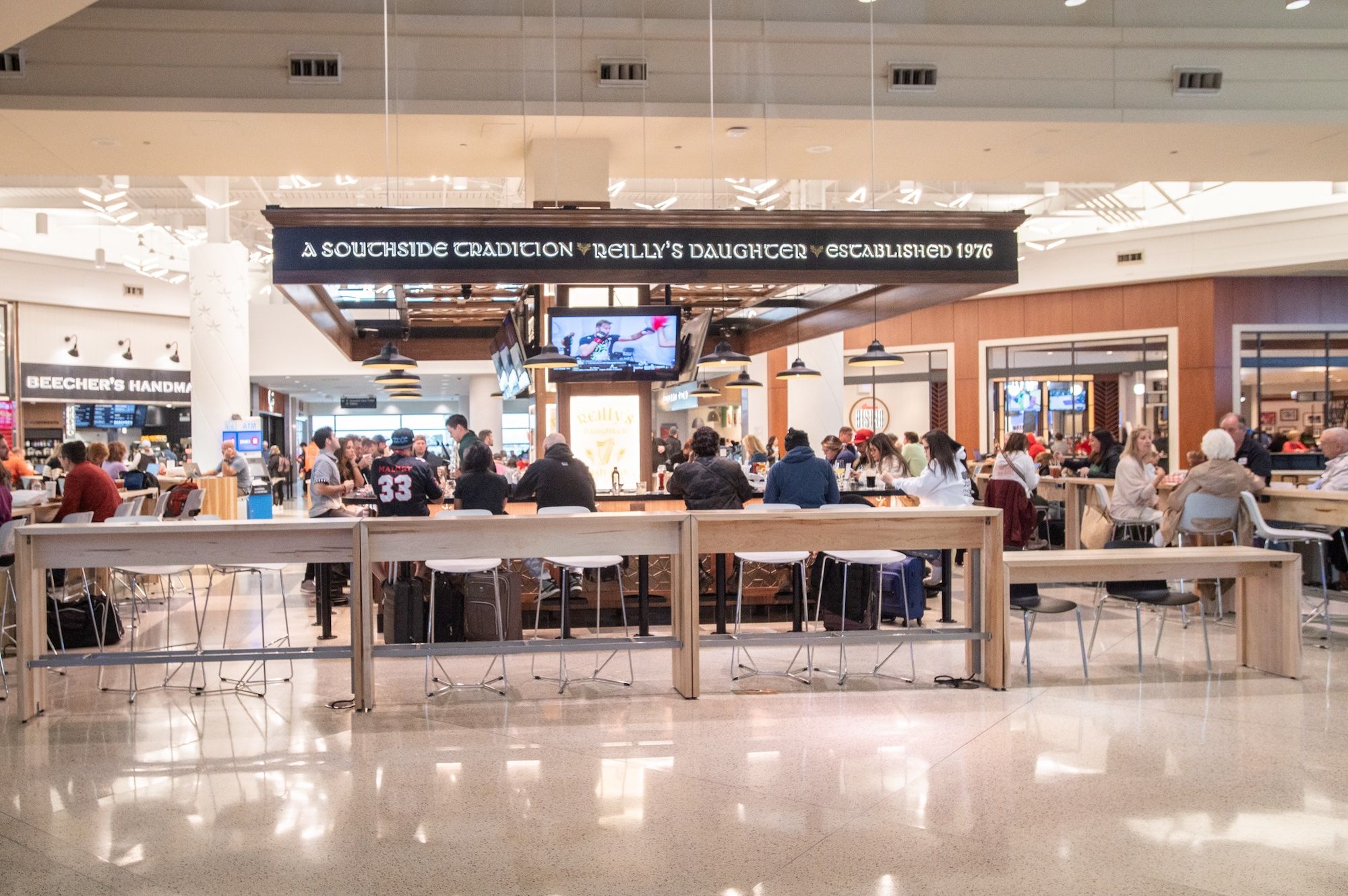 An airport food court with people sitting at a bar.