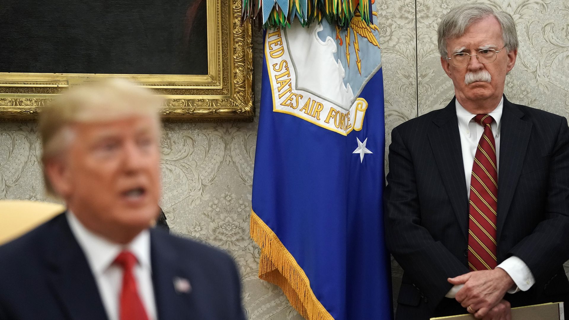 White House National Security Advisor John Bolton (R) listens to U.S. President Trump talk to reporters in the Oval Office at the White House July 18, 2019 in Washington, DC. 