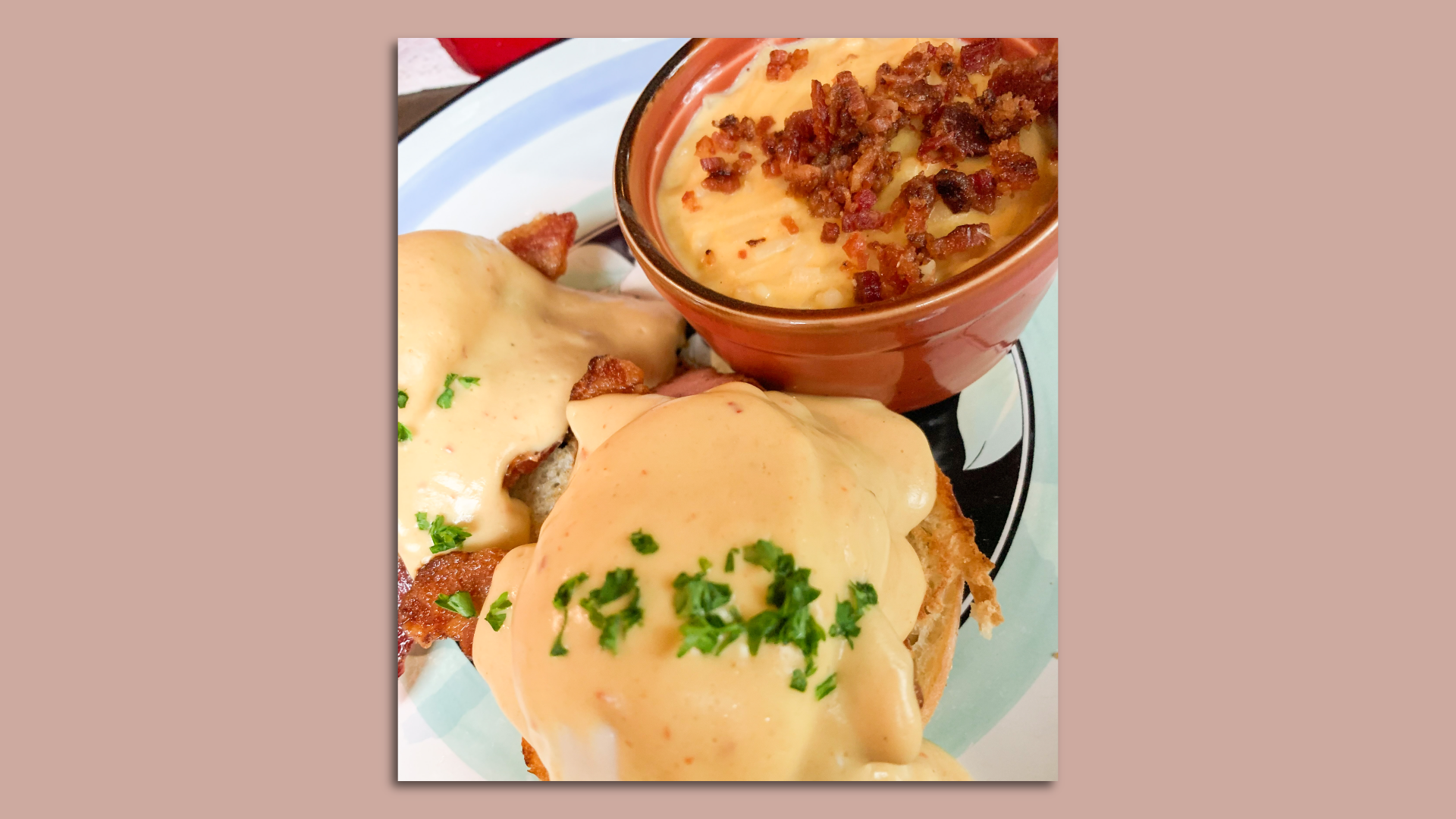 Eggs benedicts plated with a side of cheesy hashbrowns.