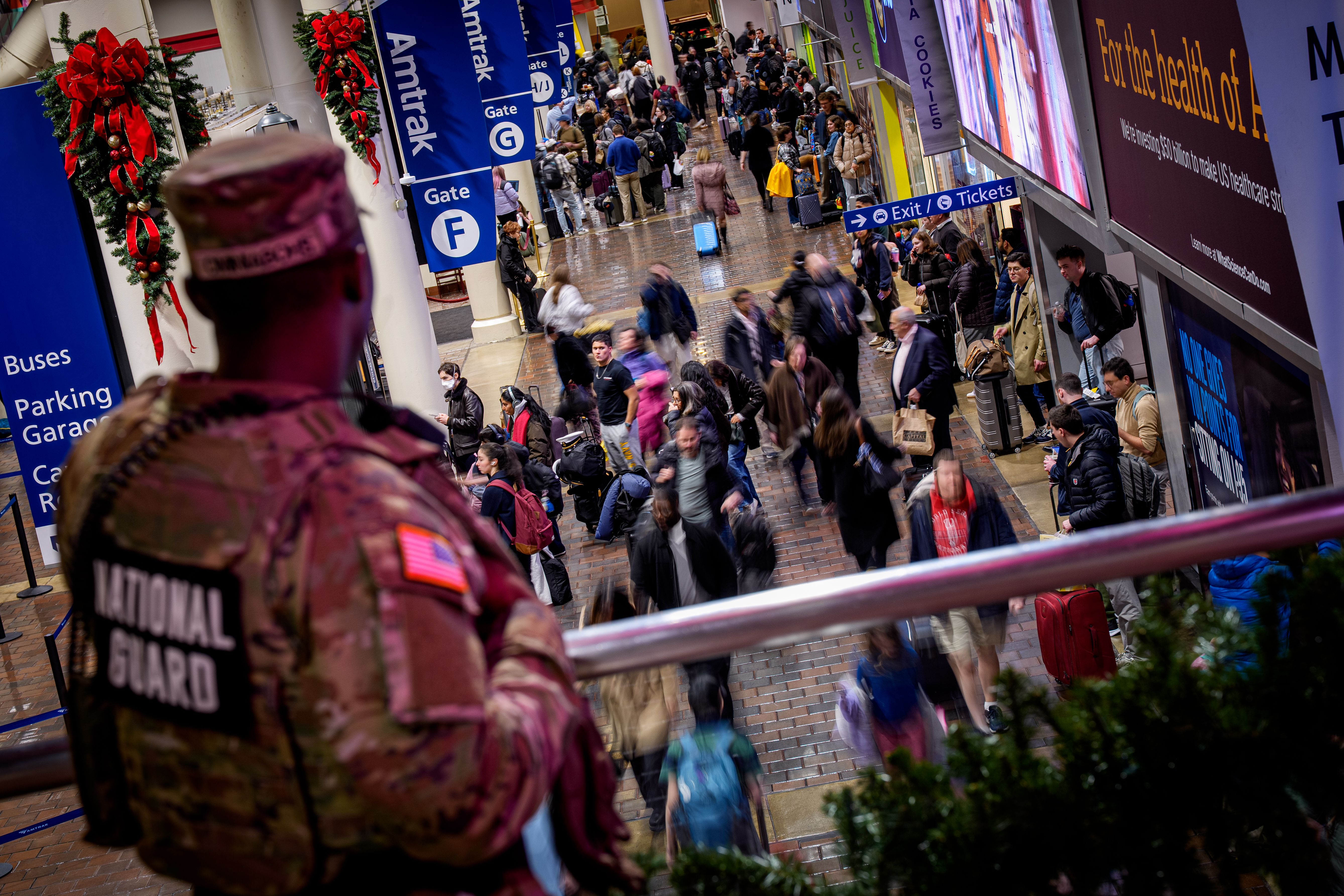 WASHINGTON, DC - NOVEMBER 25: A member of the National Guard stands above Amtrak gates as travelers move through Union Station on November 25, 2025, in Washington, DC. Thanksgiving is the busiest travel holiday of the year, and the American Automobile Association (AAA) projects a record number of tr