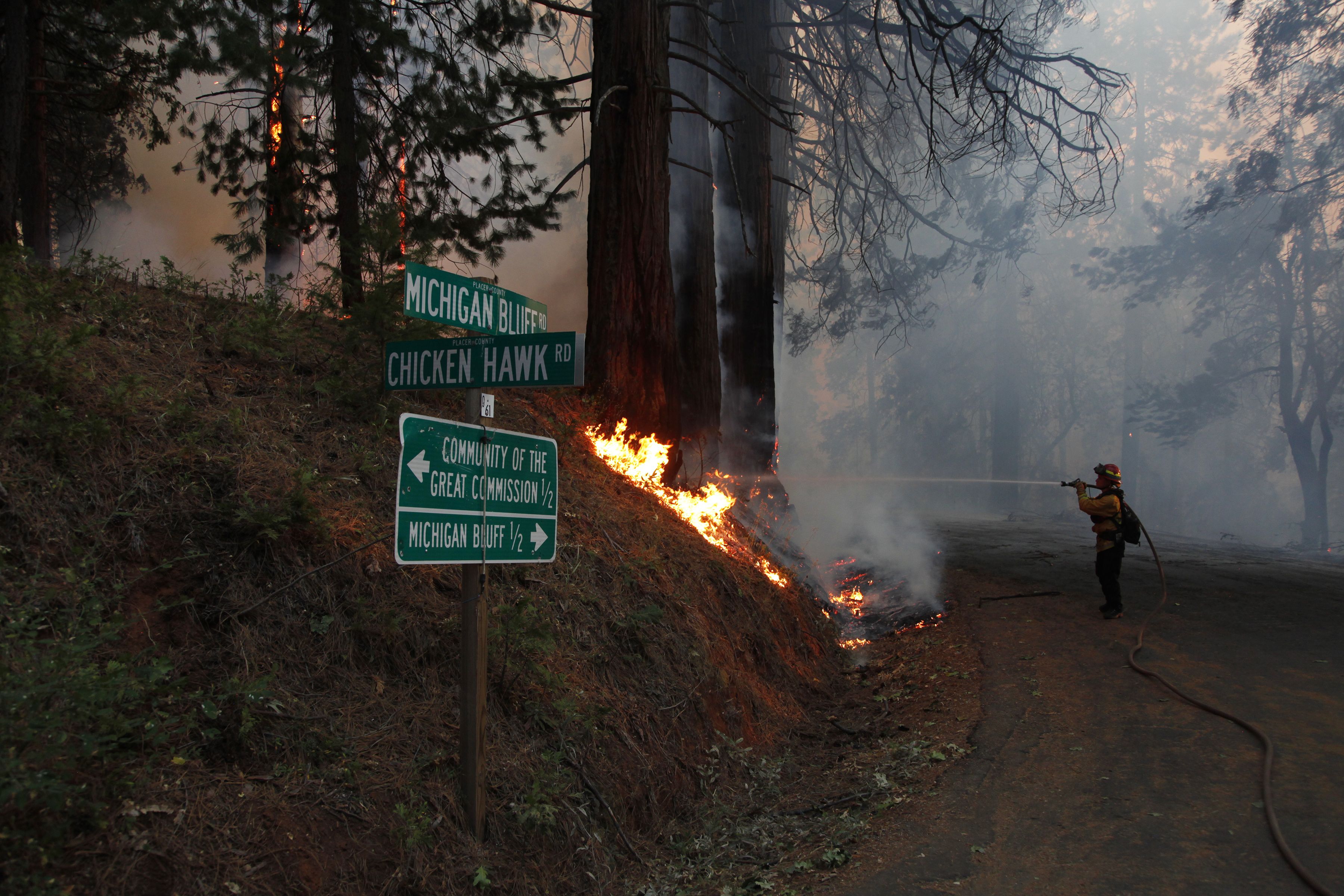 A firefighter spraying flames during the Mosquito Fire near Michigan Bluff, California Sept. 7
