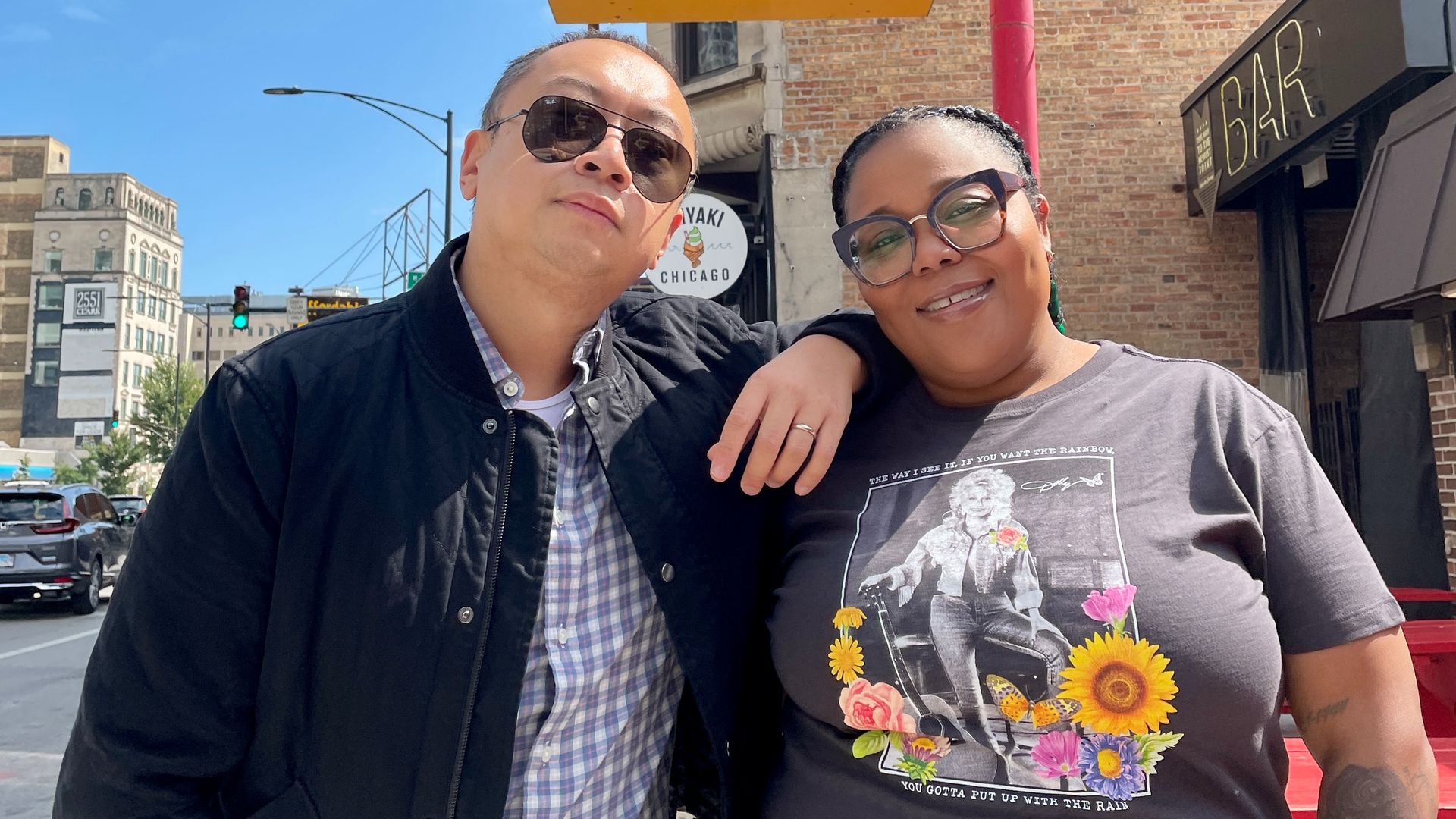Photo of two people posing for the camera on a city street 