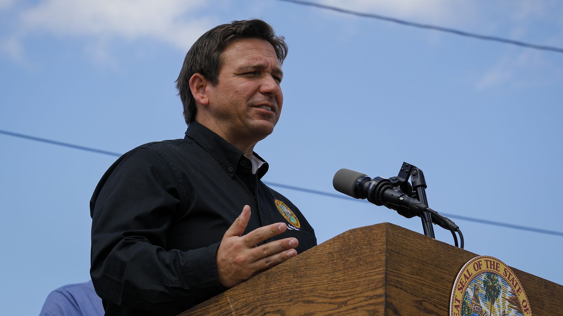 Photo of Ron DeSantis speaking from a podium at an outdoor event