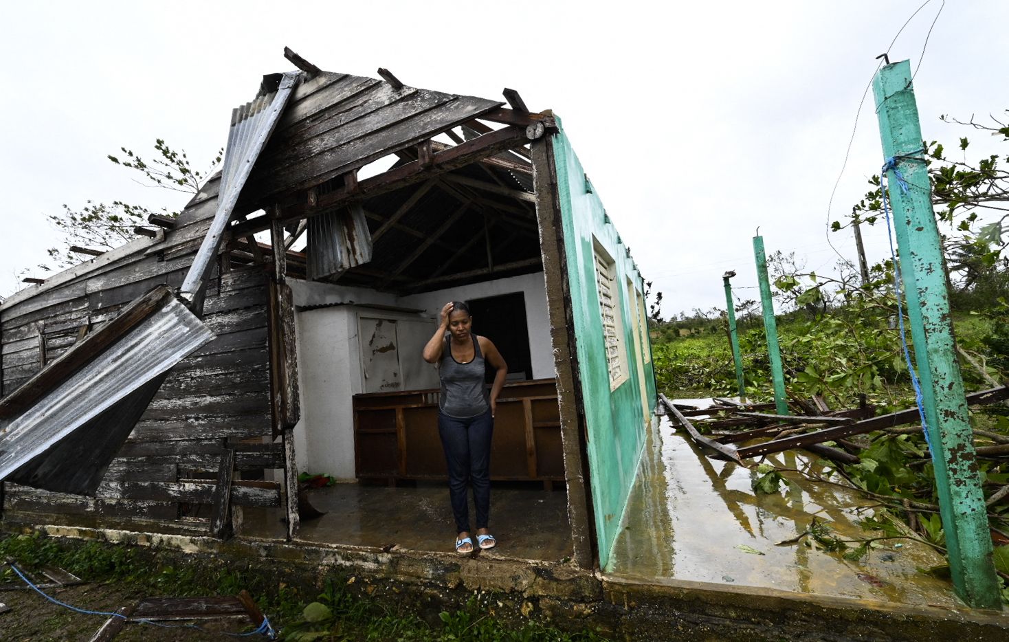 woman stands in front of her destroyed home in Cuba